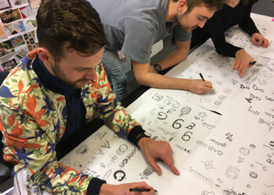 Three people working together to sketch logo concepts
