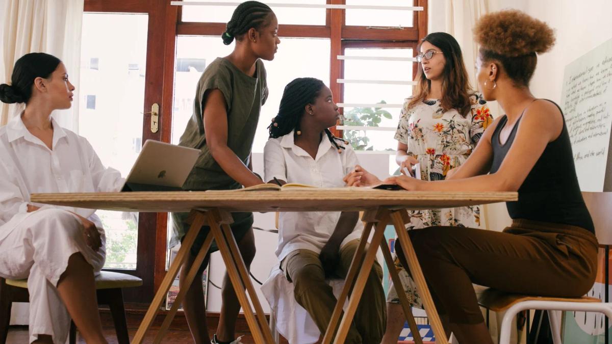 Tree diverse women are seating at the table and chatting