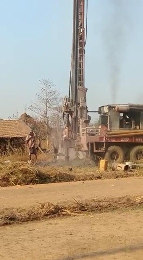 A drilling rig working beside buildings at the site.