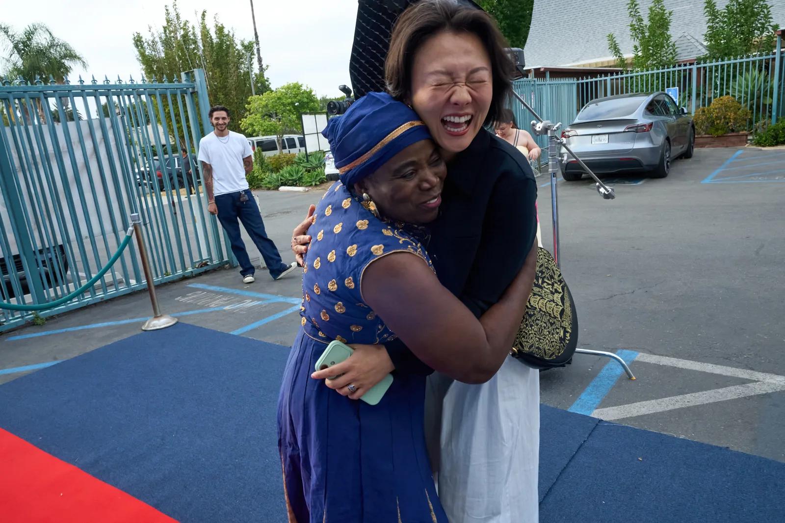 Two people sharing a joyful embrace as guests arrive at the Gala.