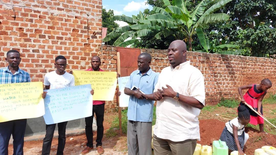 The Ntawo-Mukono community gathered at the build site with thank-you signs.