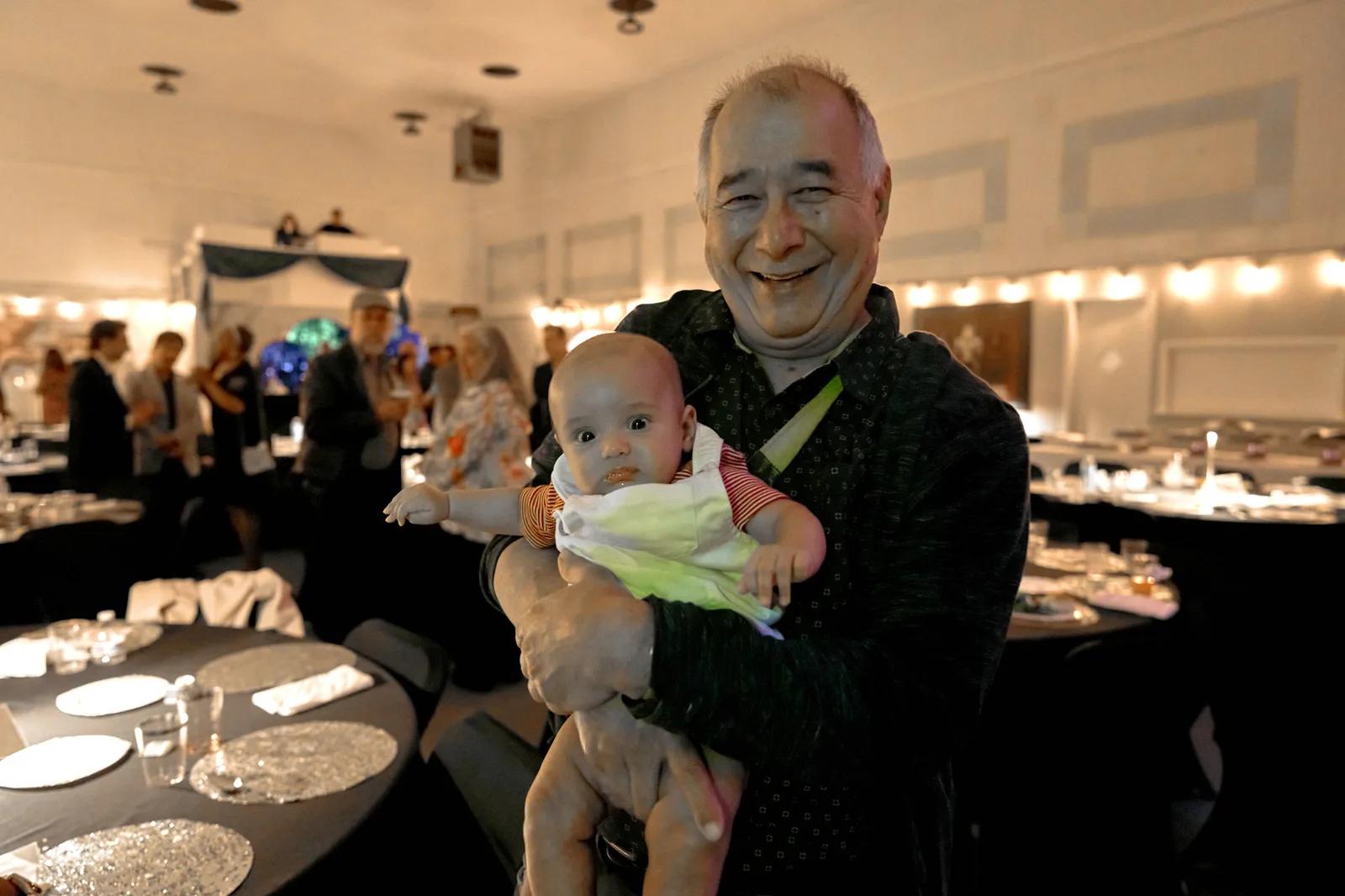 A Gala guest holding a baby during the evening.