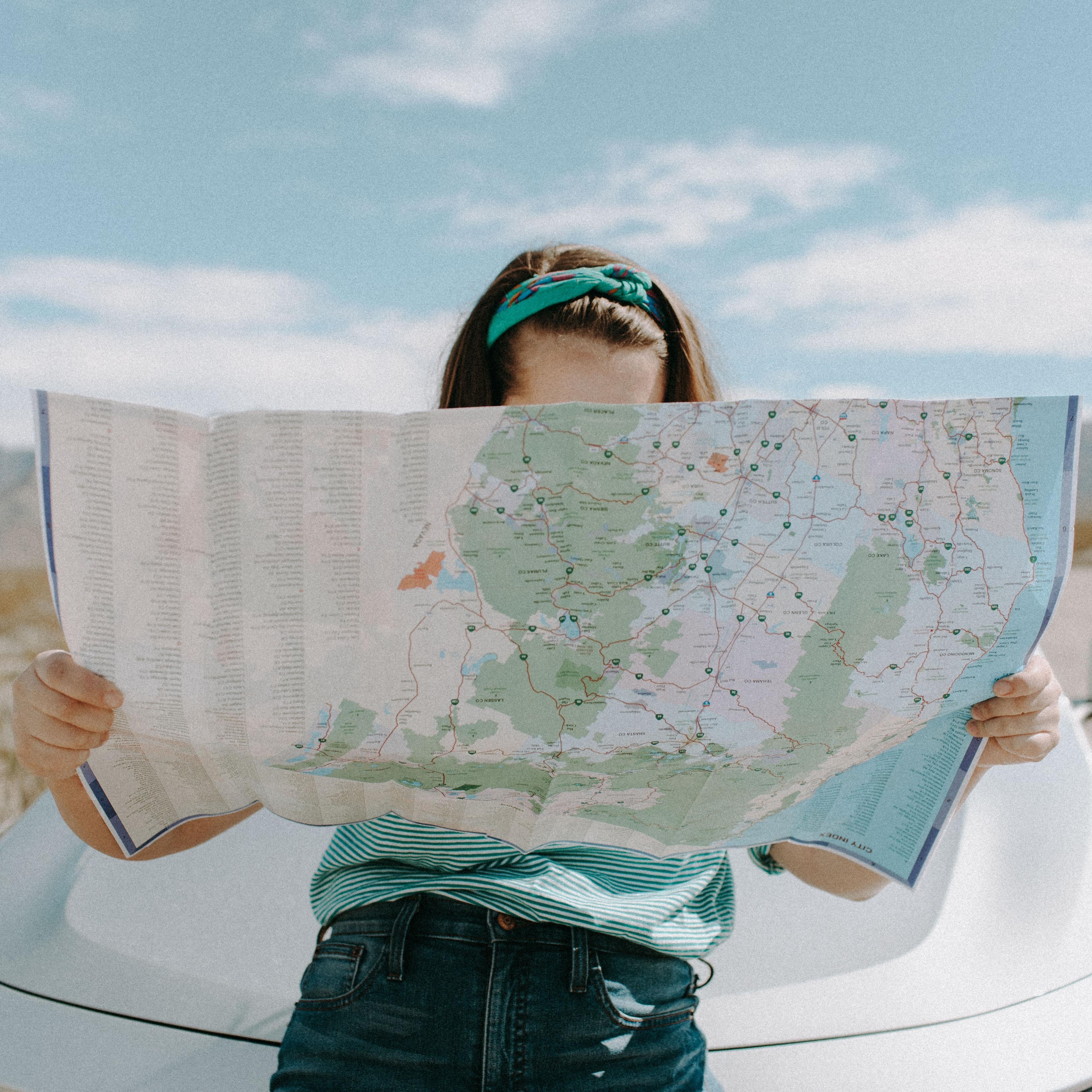 Nainen tarkastelee karttaa auton edessä.