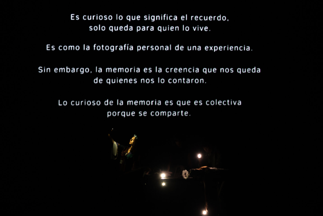 Texto proyectado sobre fondo negro: "lo curioso de la memoria es que es colectiva porque se comparte"