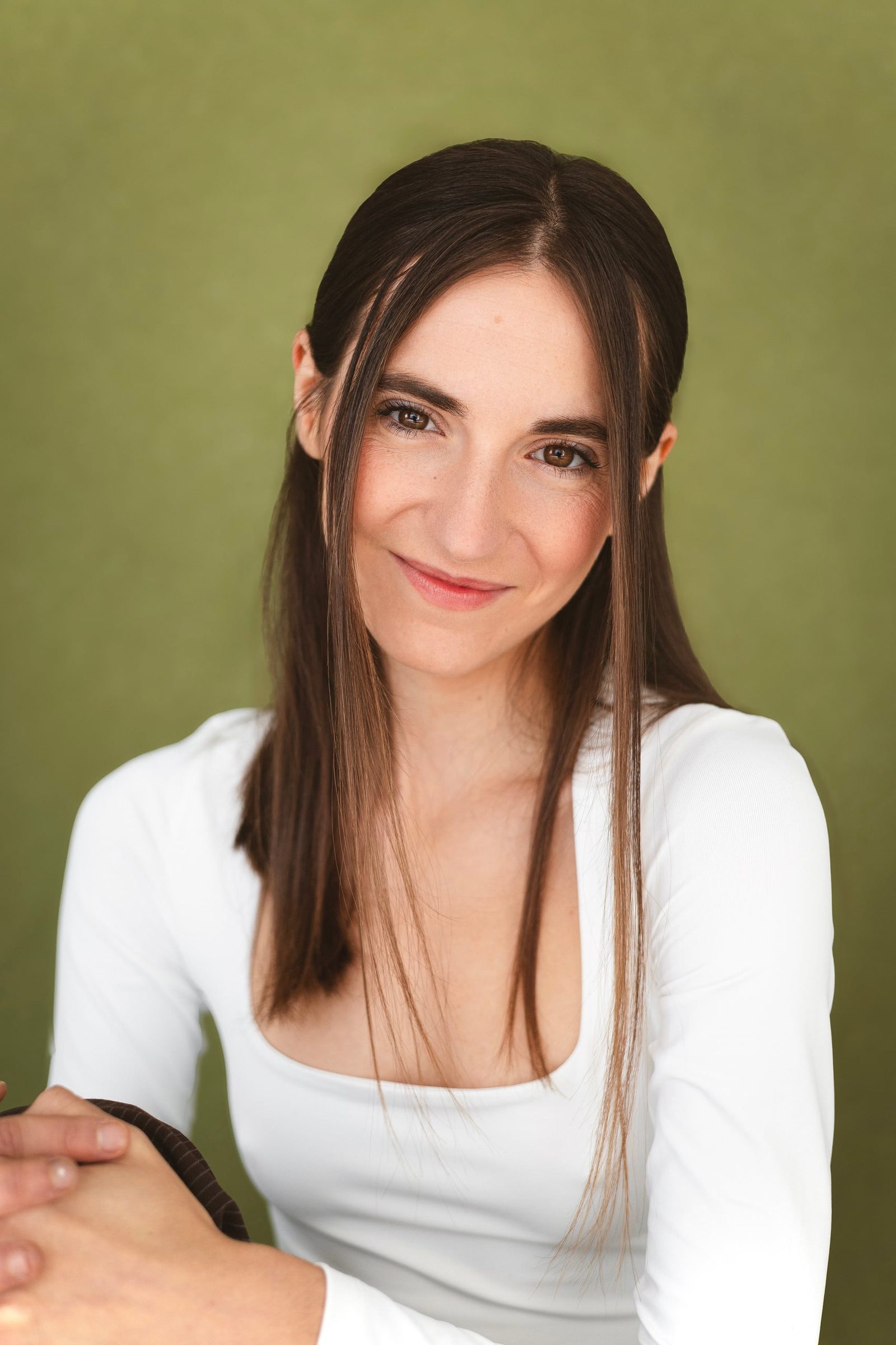 Cecilia Mansilla sonriendo con camiseta blanca sobre fondo verde oliva