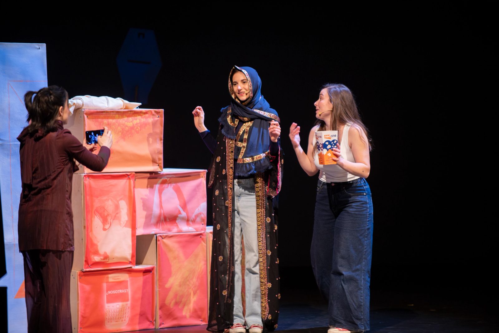 Tres actrices conversando en escena junto a unos módulos de cartón