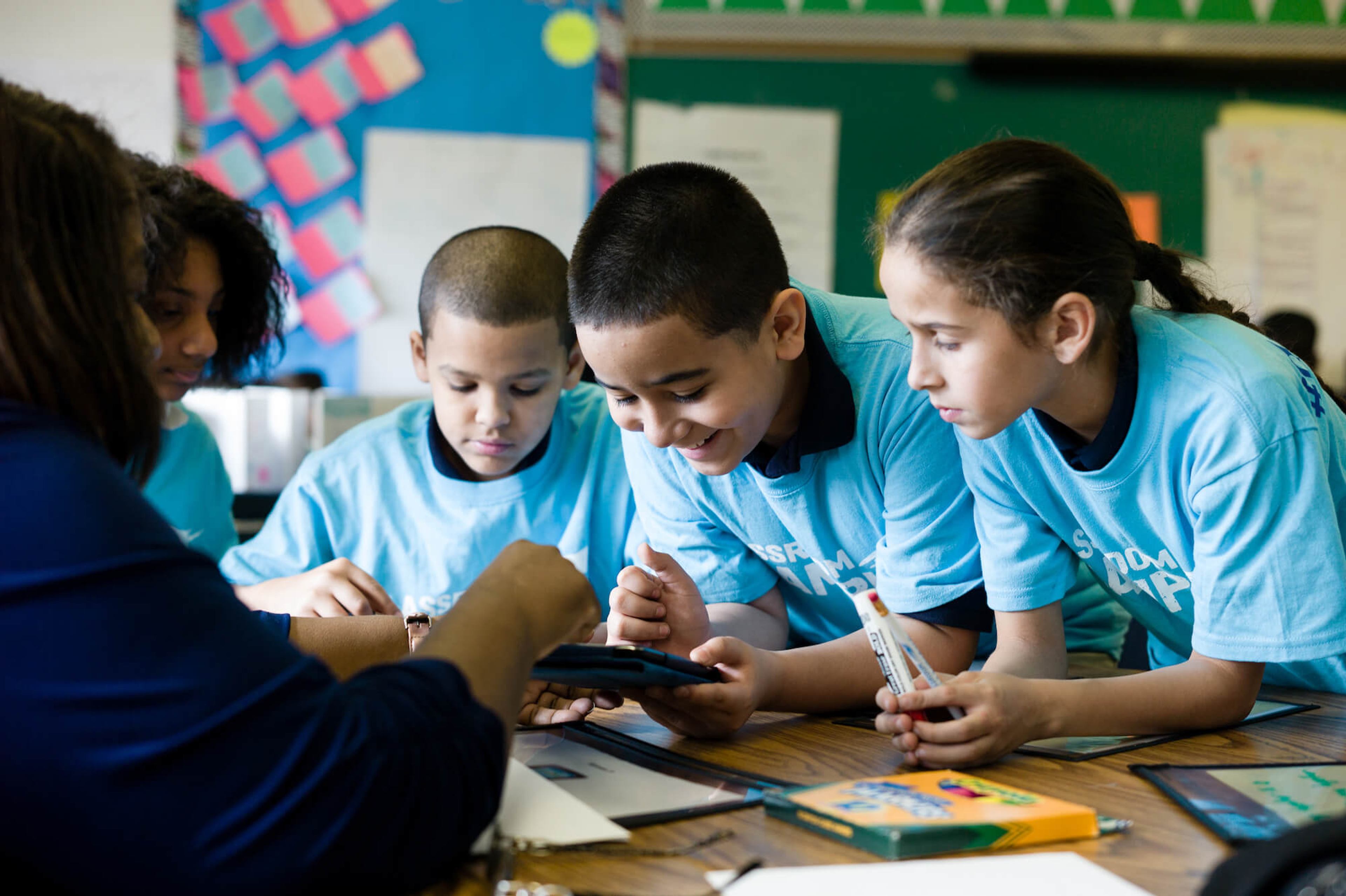 Children in Classroom Champions shirts work on a group project together