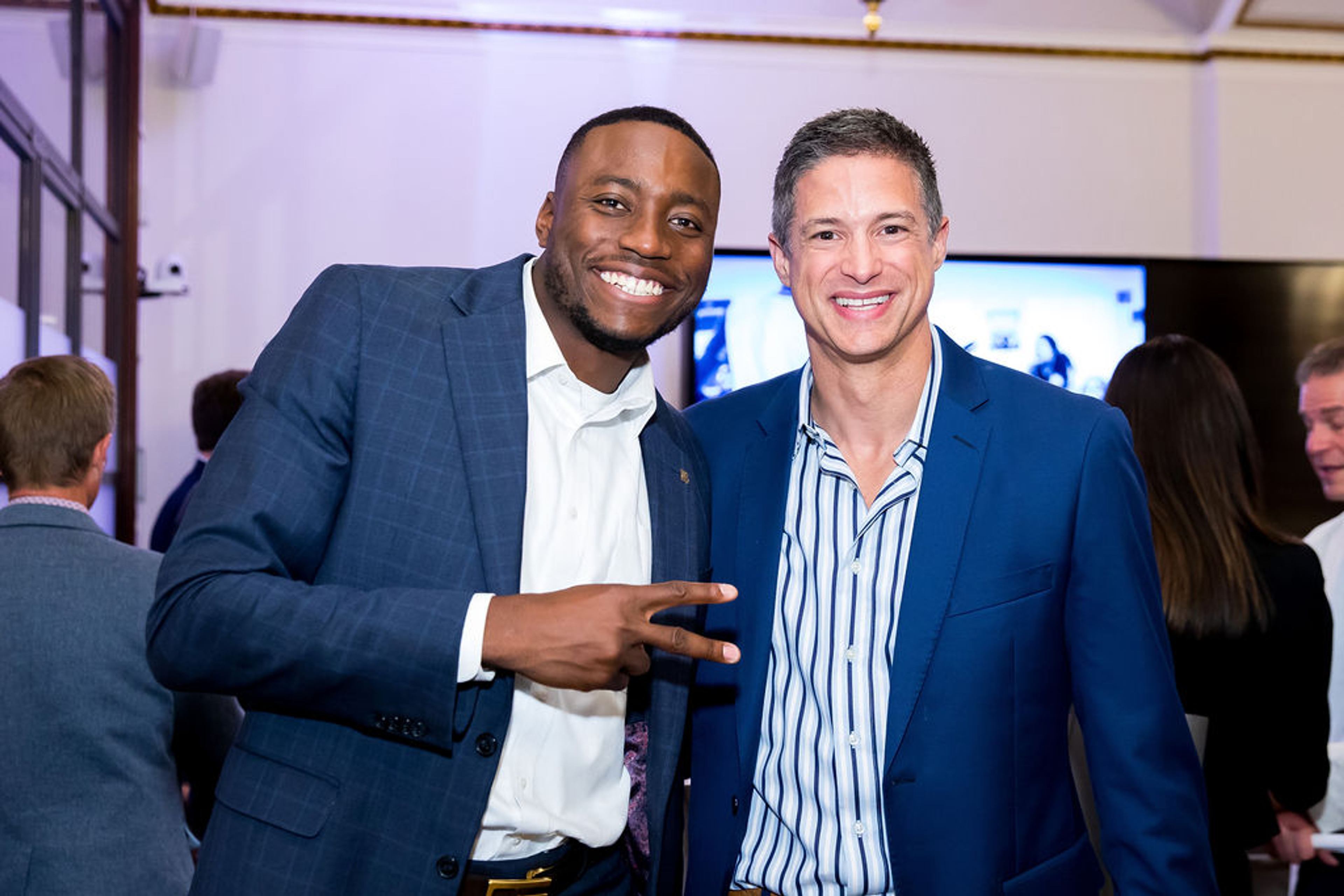 Two men in suits smile together at a Classroom Champions Circle event.