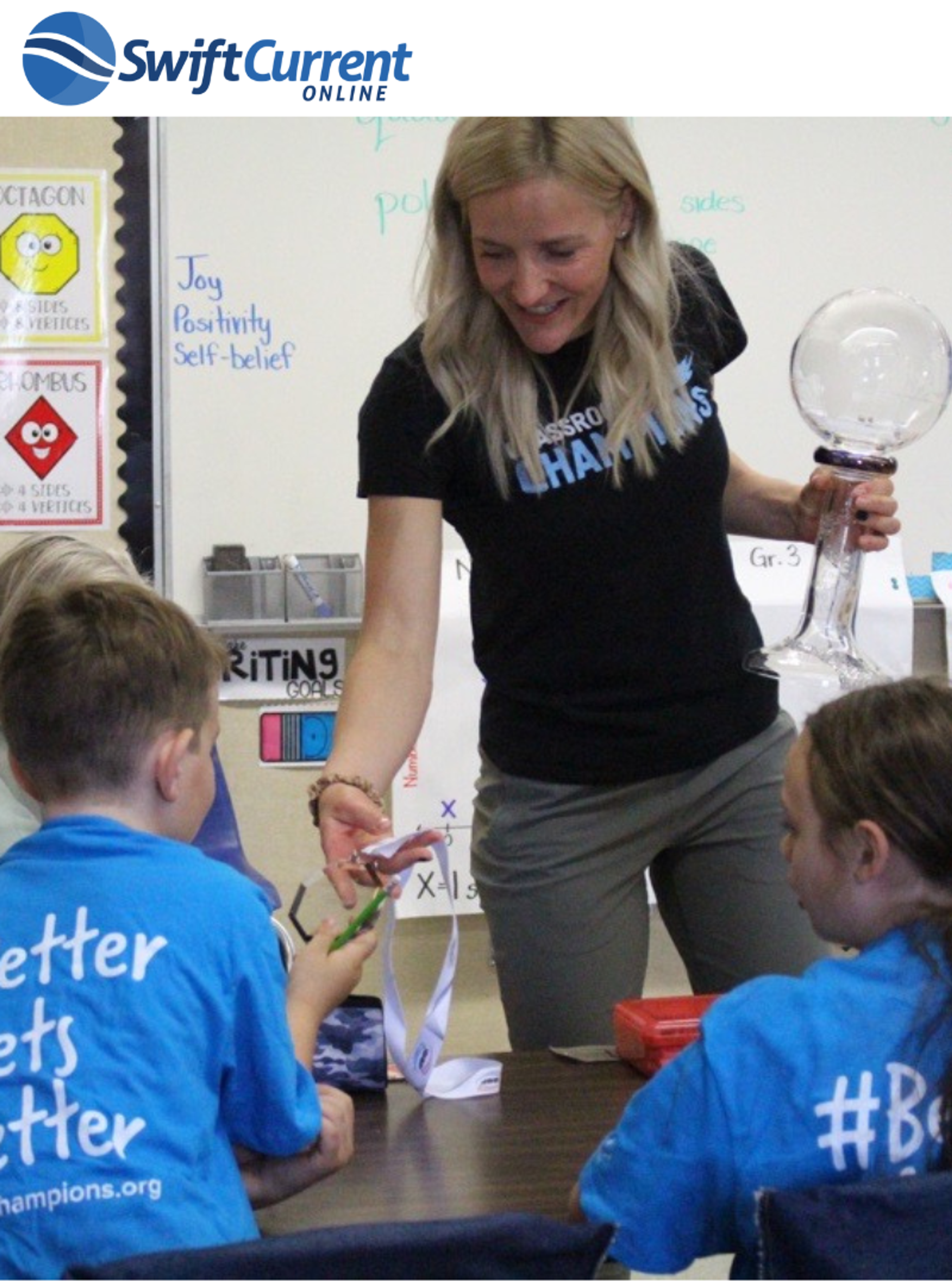 A Classroom Champions mentor gives a medal to a student in a classroom activity.