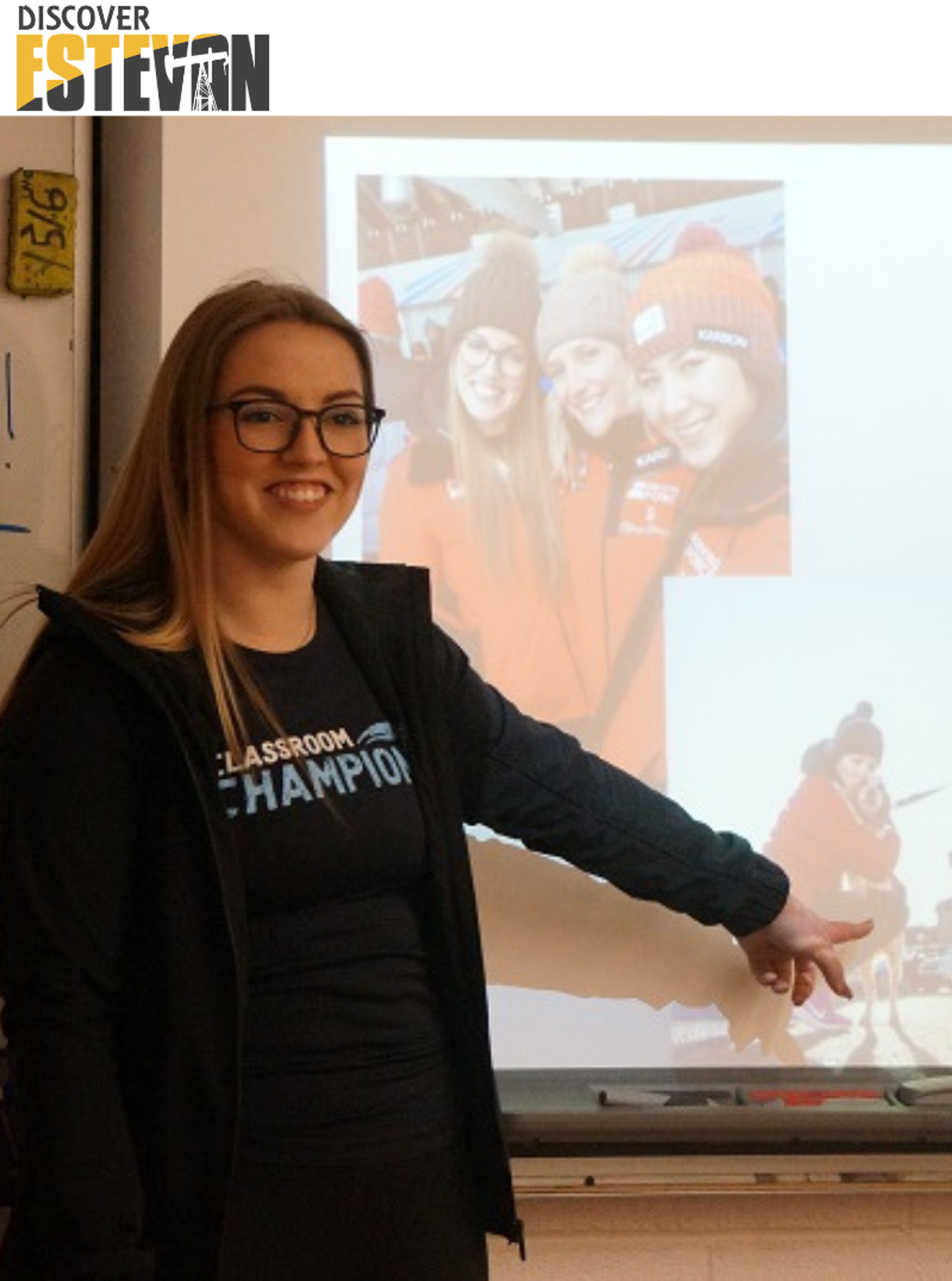 A Classroom Champions mentor presents to students, pointing to a slideshow photo of athletes bundled up outdoors.