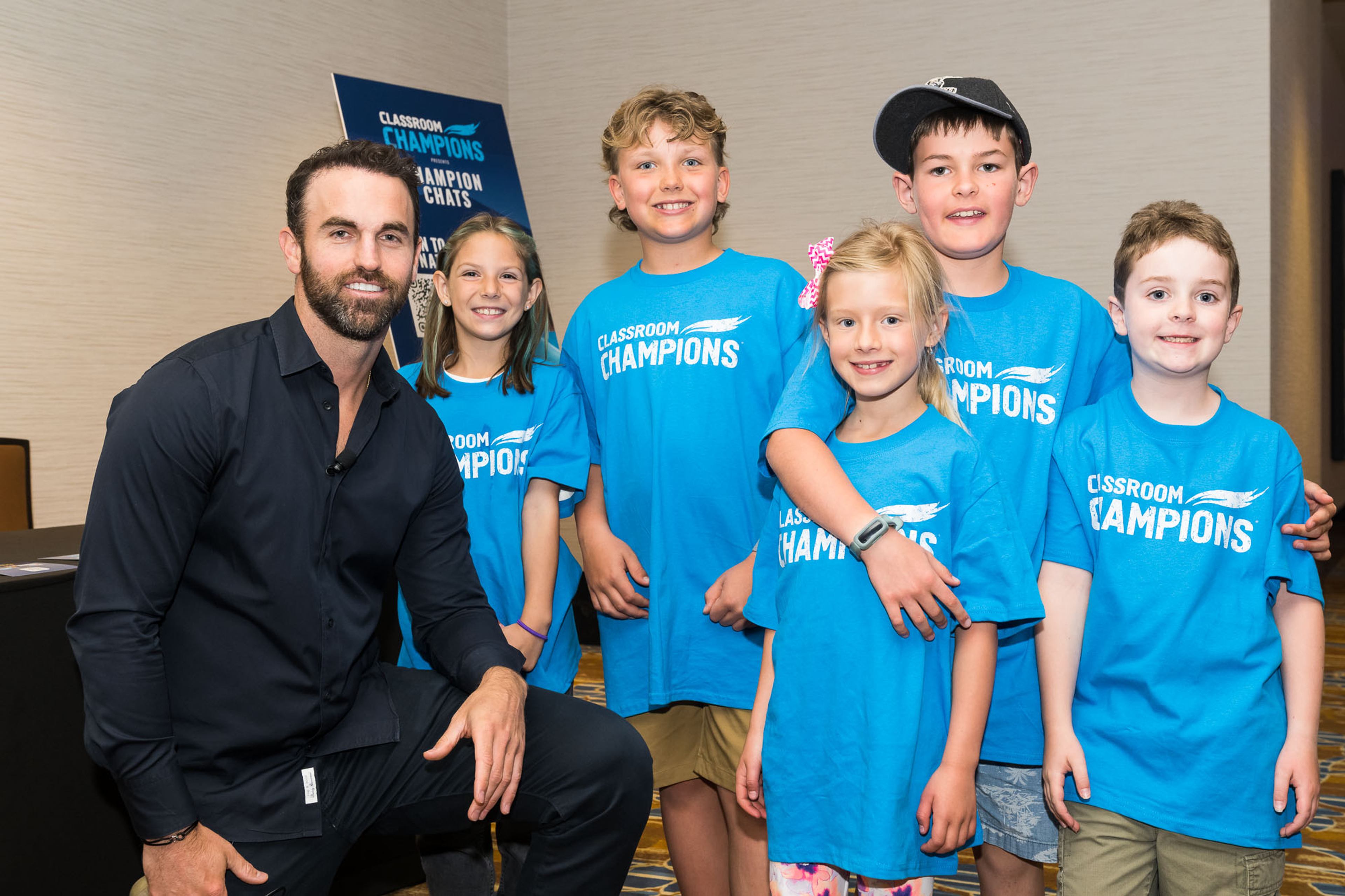 Andrew Ladd poses with students wearing Classroom Champions T-shirts at a Champion Chats event.