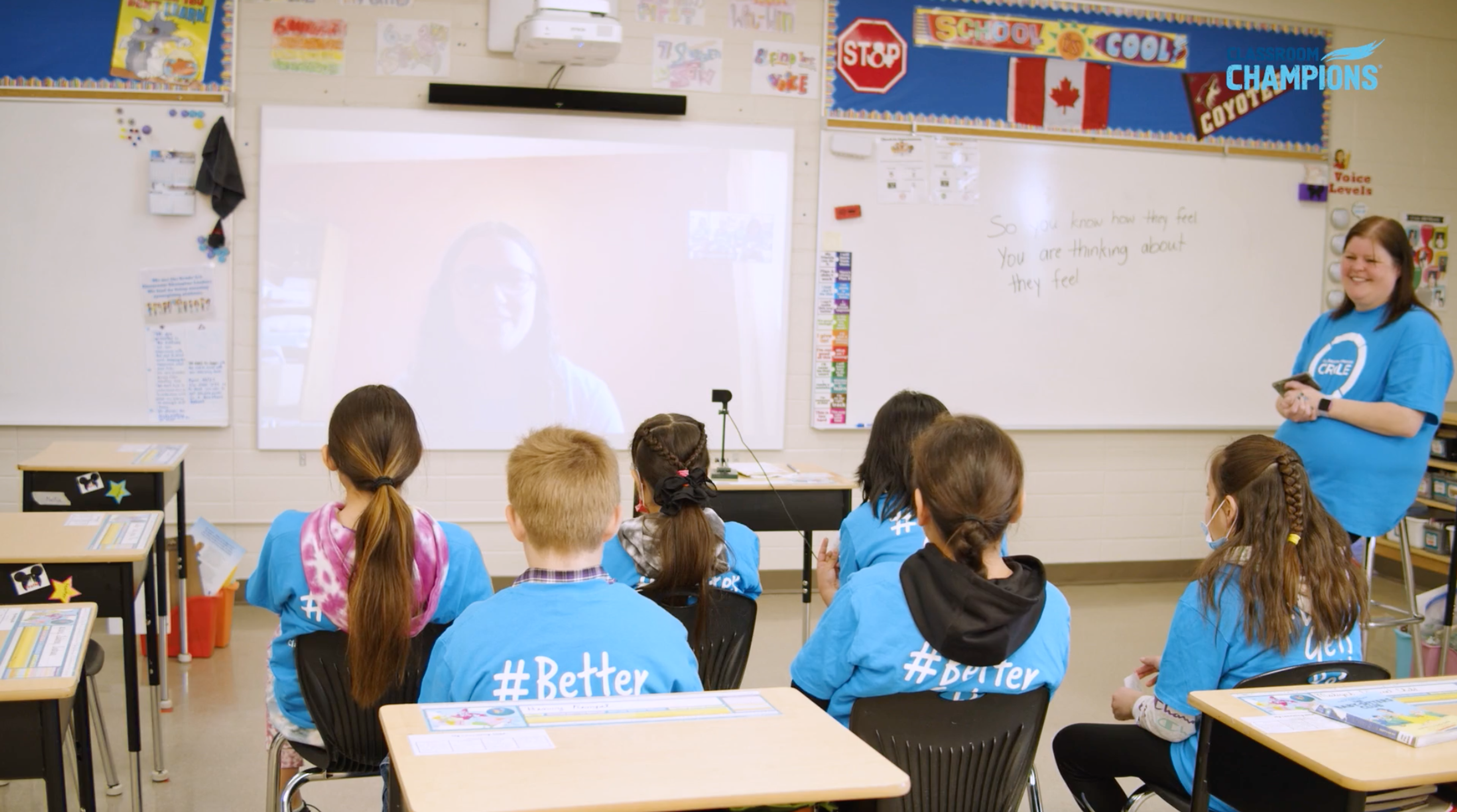 Students wearing #Better shirts watch a mentor speak via video call during a Classroom Champions lesson.