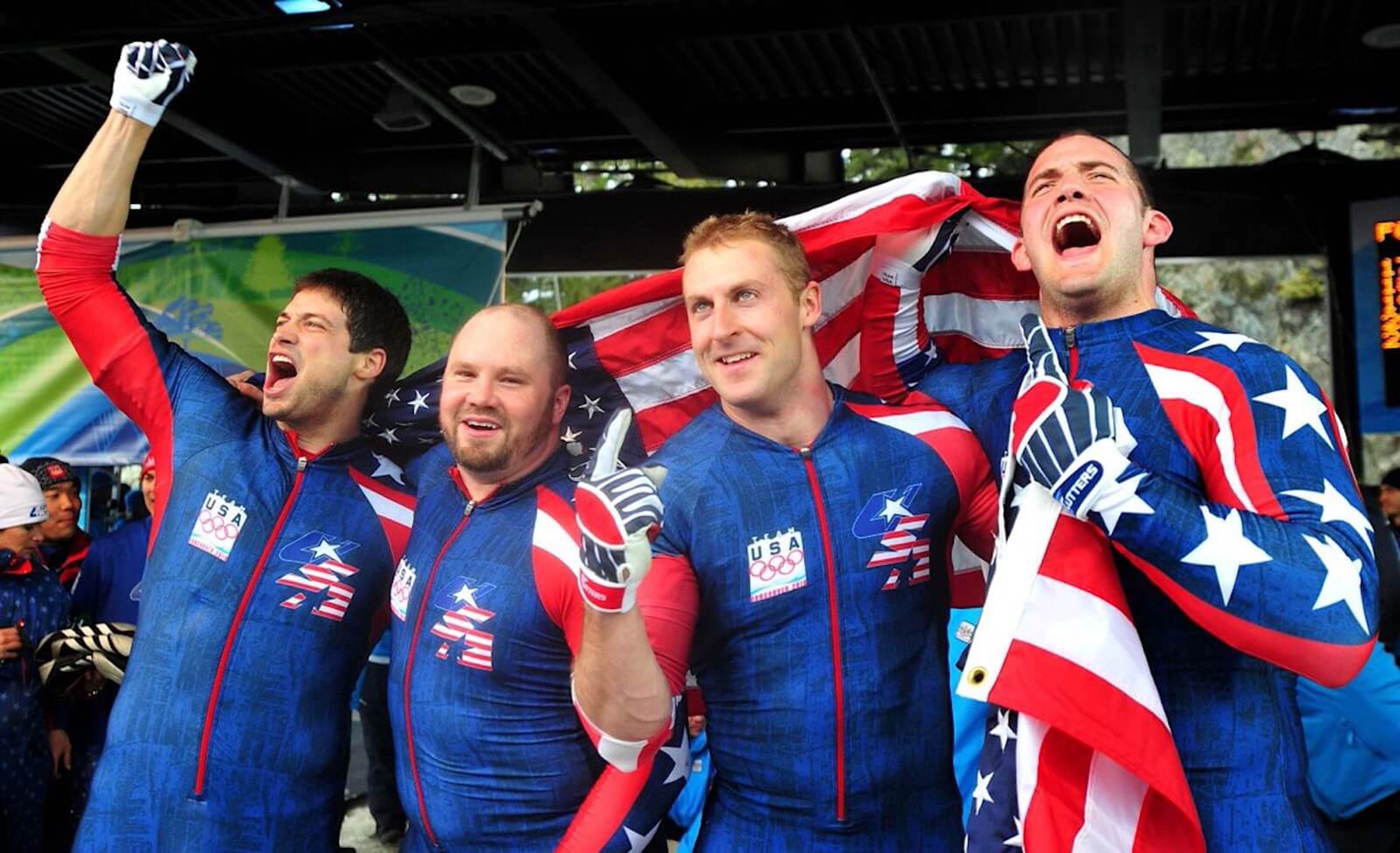 Four athletes in team USA gear cheer after an event