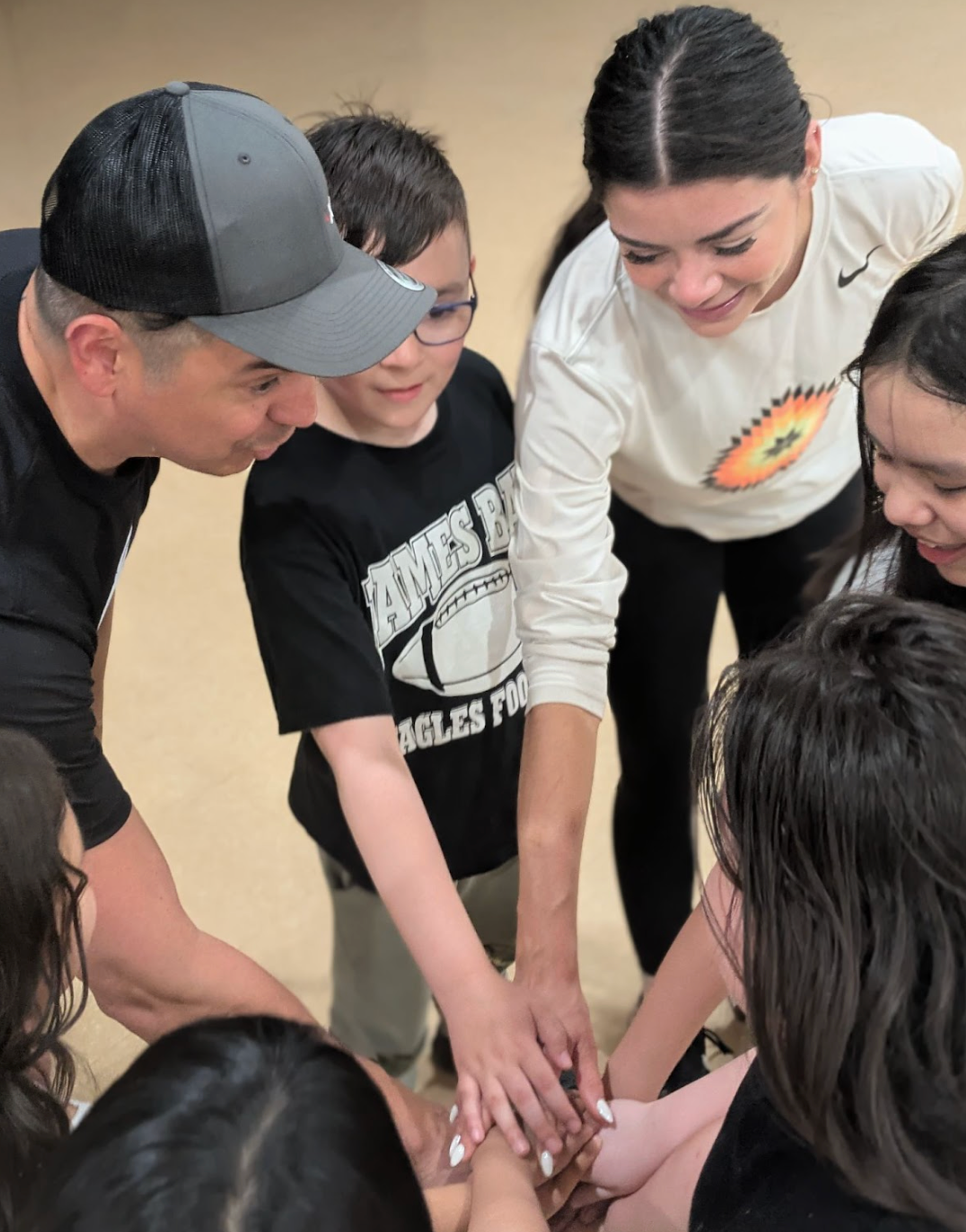 An athlete mentor and students stack hands together in a team huddle during a Chisasibi classroom visit.