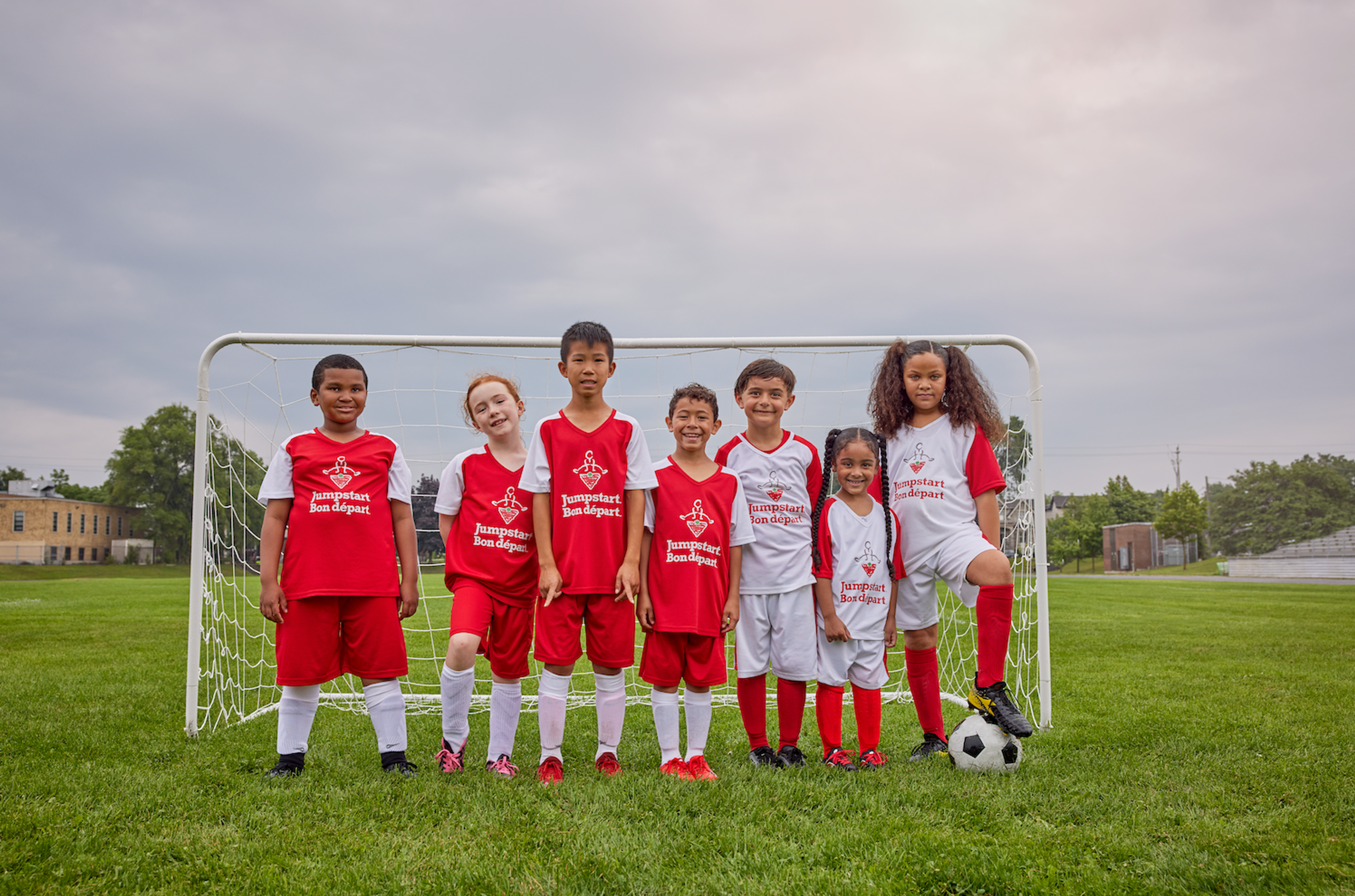 A youth soccer team in Jumpstart Bon départ jerseys poses together in front of a goal.