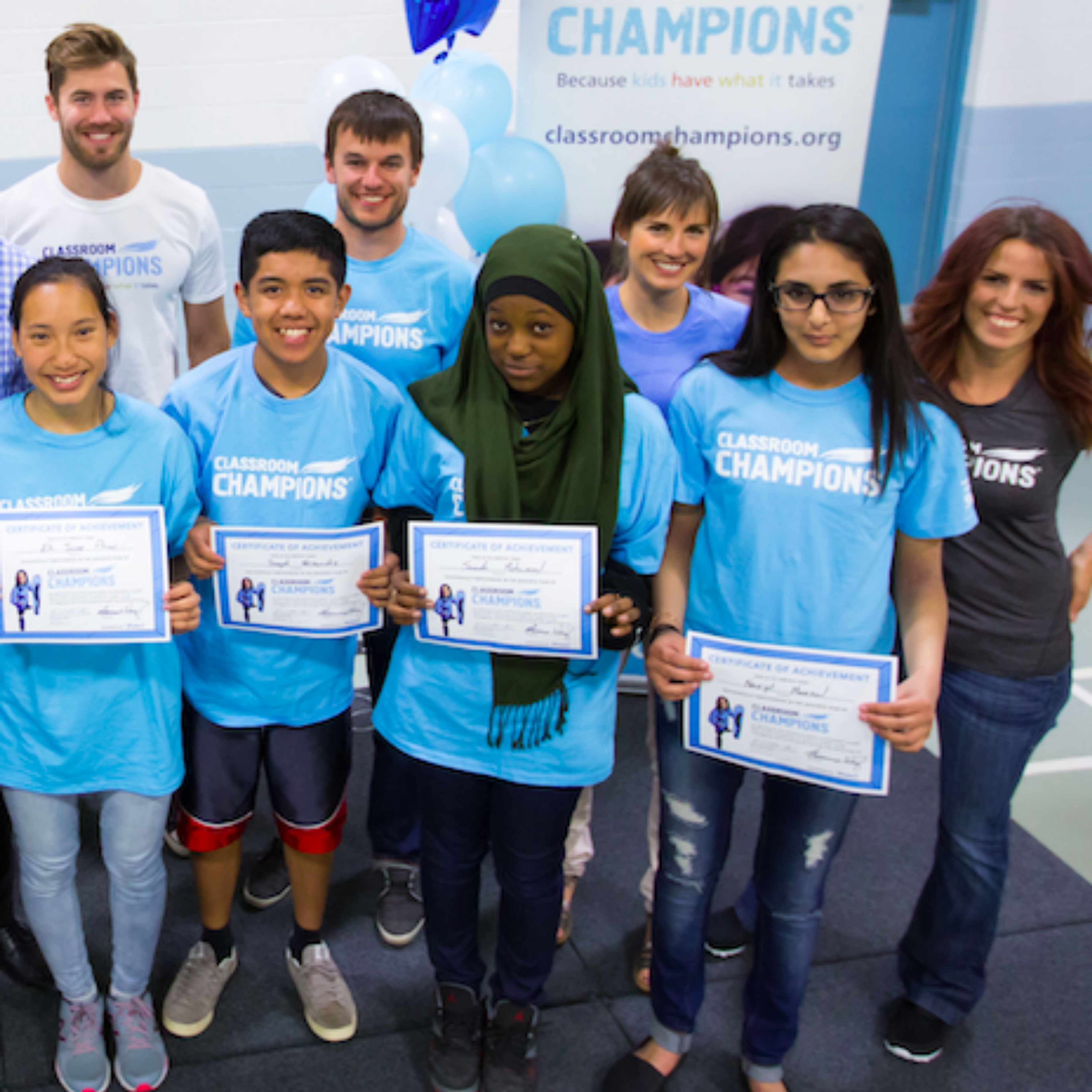 Students hold Classroom Champions certificates of achievement alongside mentors at an event.