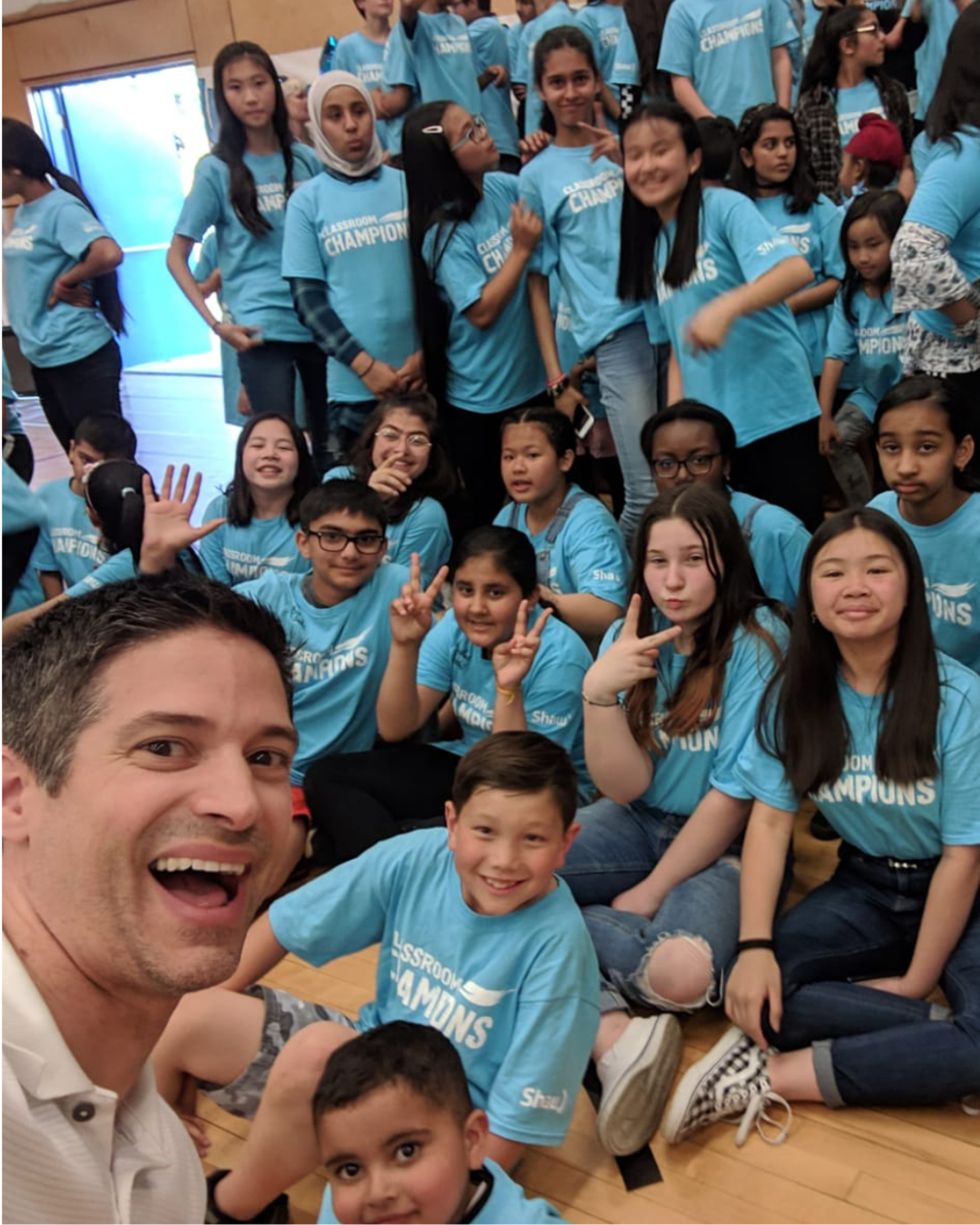 A mentor takes a group selfie with students wearing Classroom Champions T-shirts.