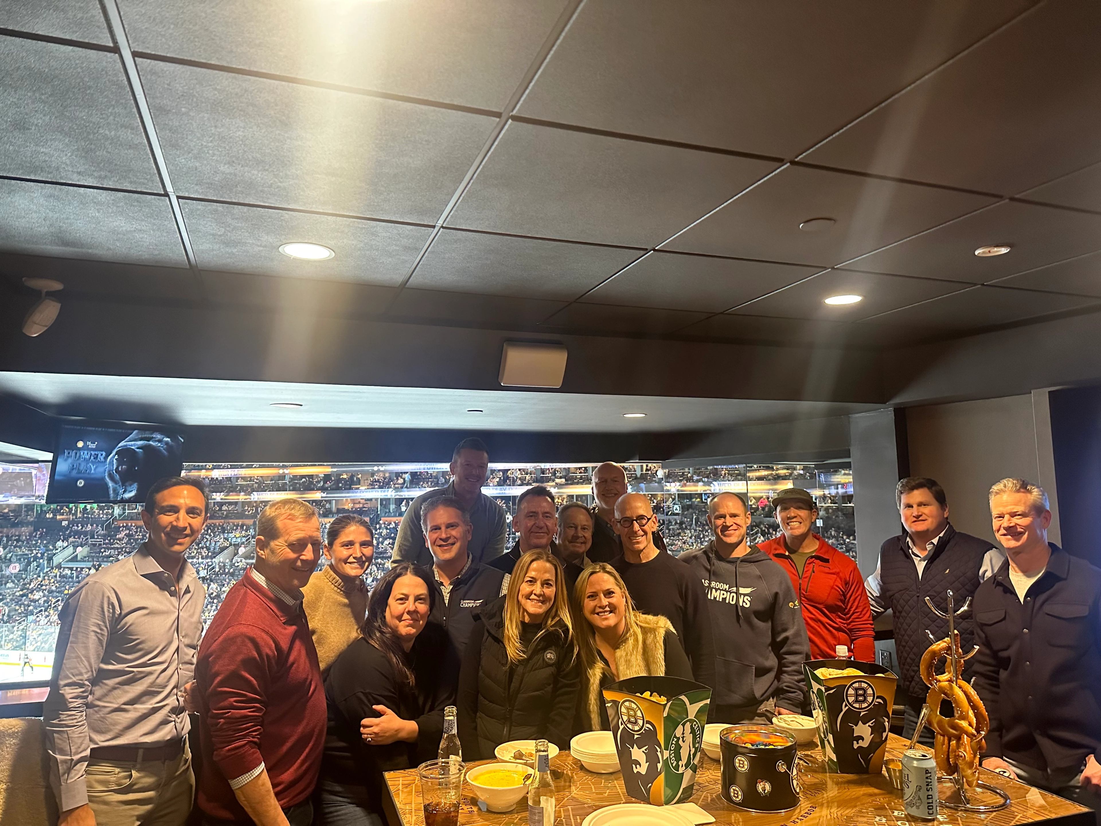 Classroom Champions supporters gather for a group photo at a Boston Bruins hockey game suite.