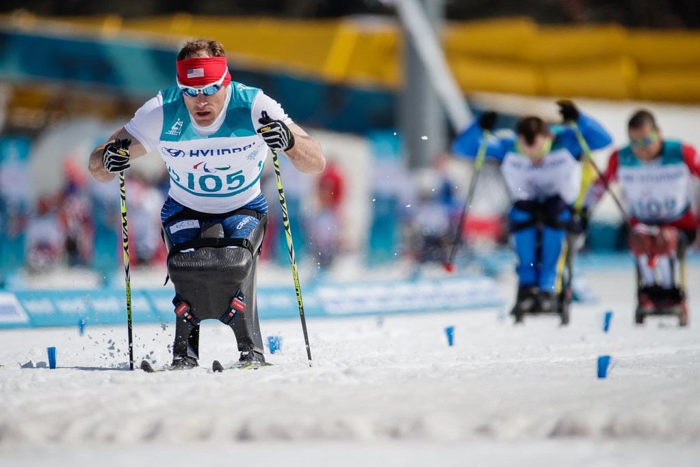Dan Cnossen races in a sit-ski during a Paralympic cross-country skiing competition.