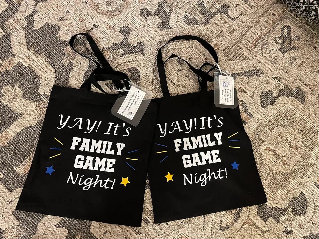 Two black tote bags printed with "Yay! It's Family Game Night!" for a classroom service learning project.