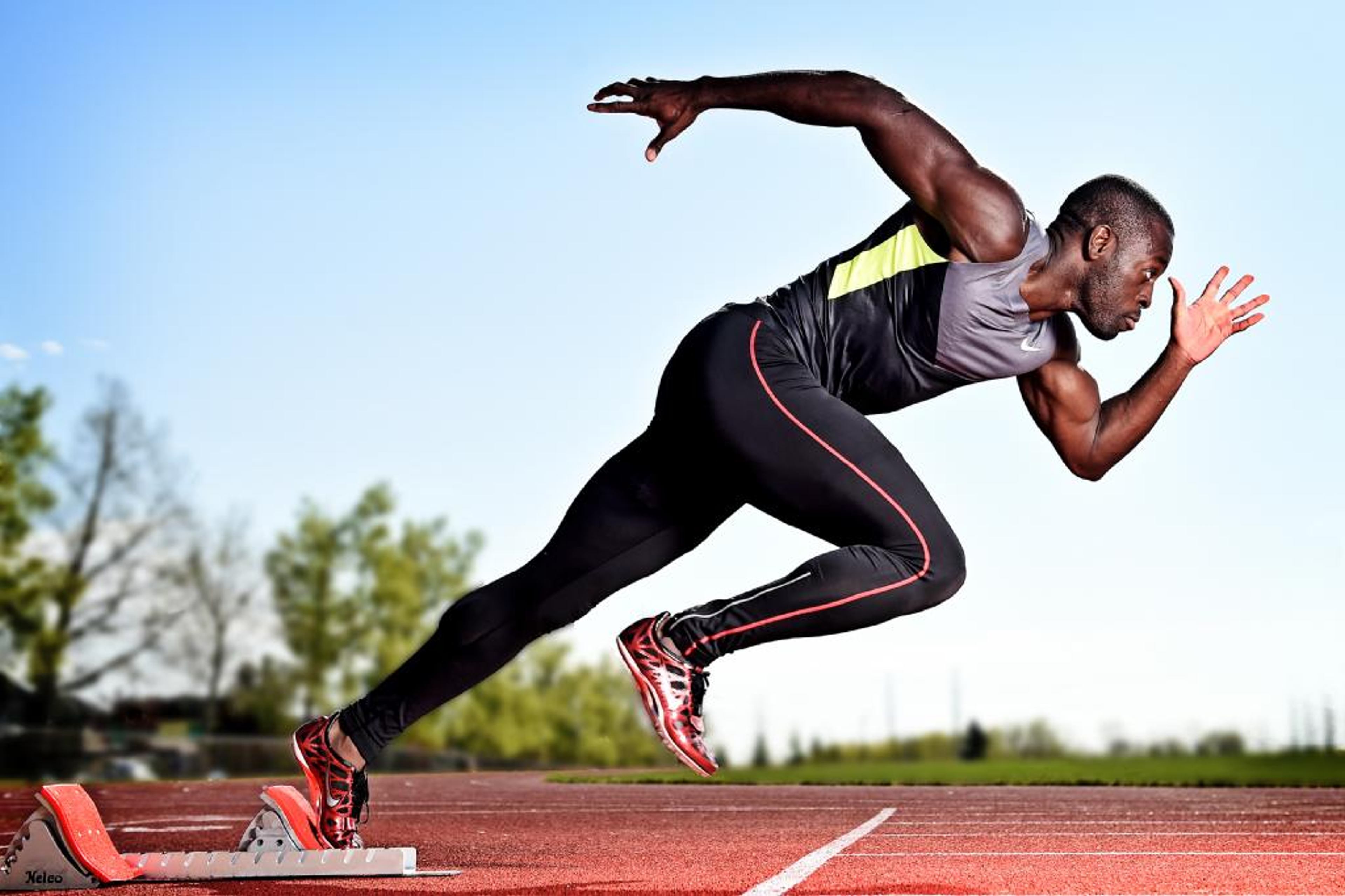 A sprinter explodes out of the starting blocks on a track.