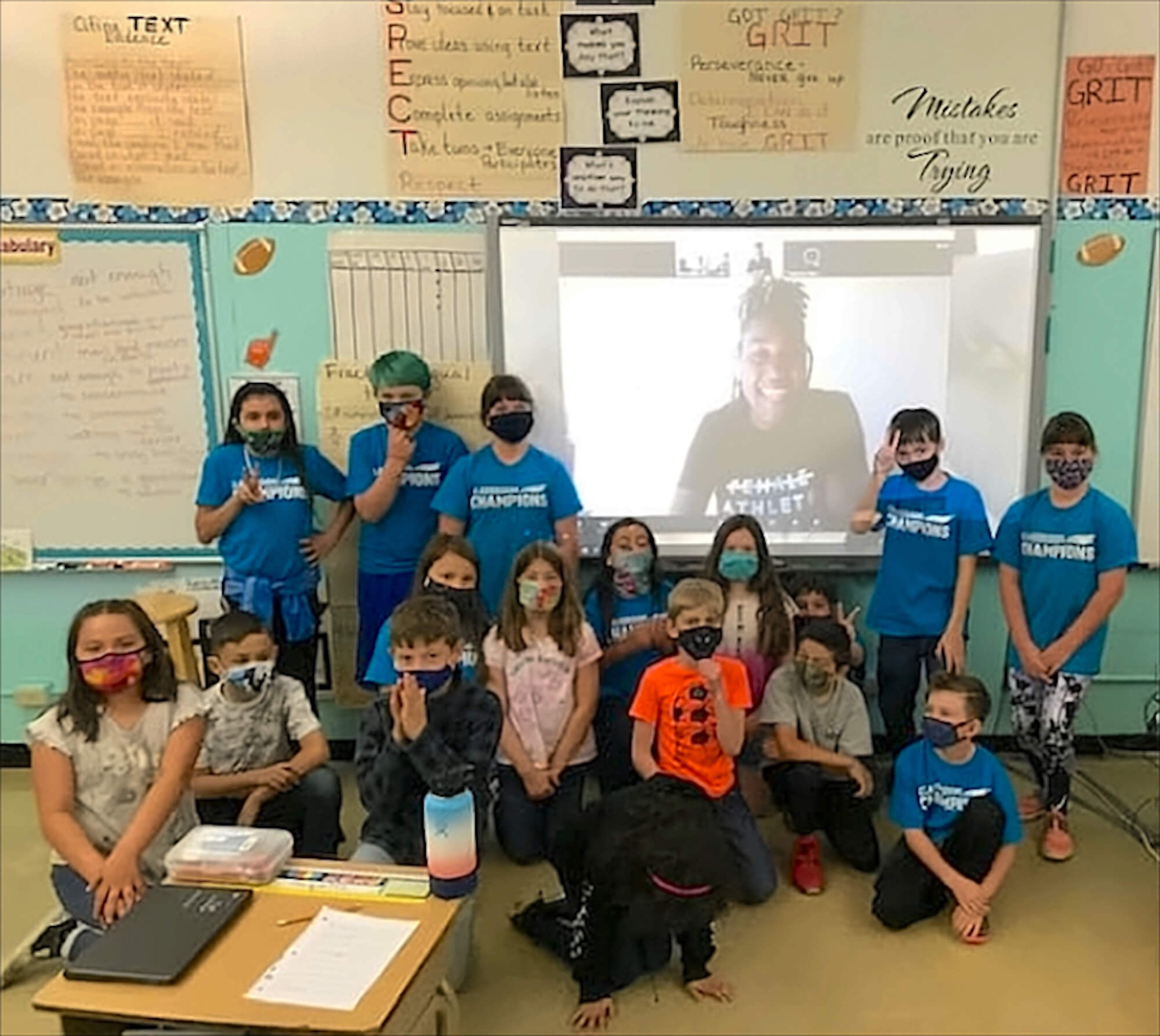 A group of students take a photo in front of a classroom screen