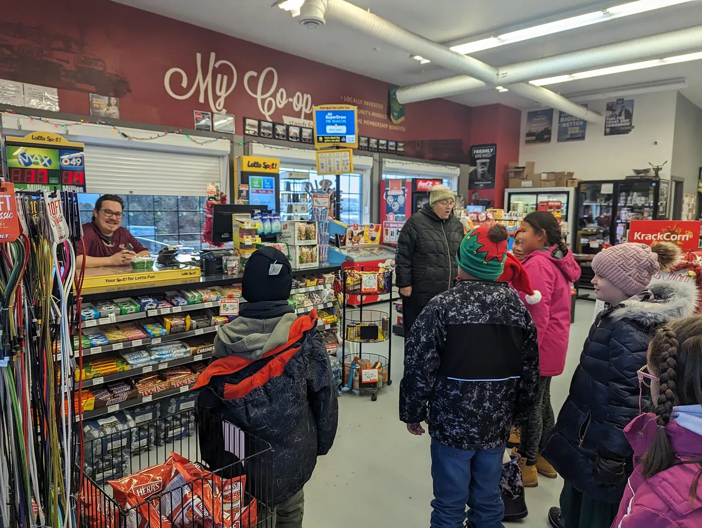 Students bundled in winter coats gather at a co-op store checkout as part of a community service learning project.