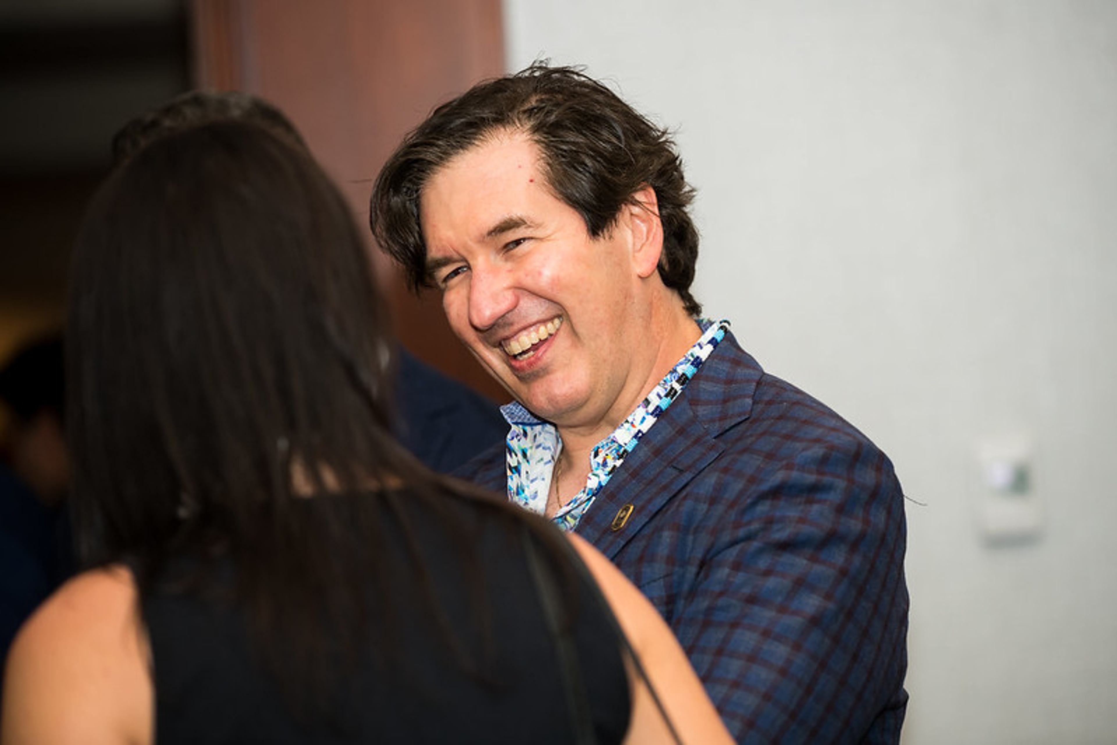 A man laughs while conversing with someone at a Champions Circle event.