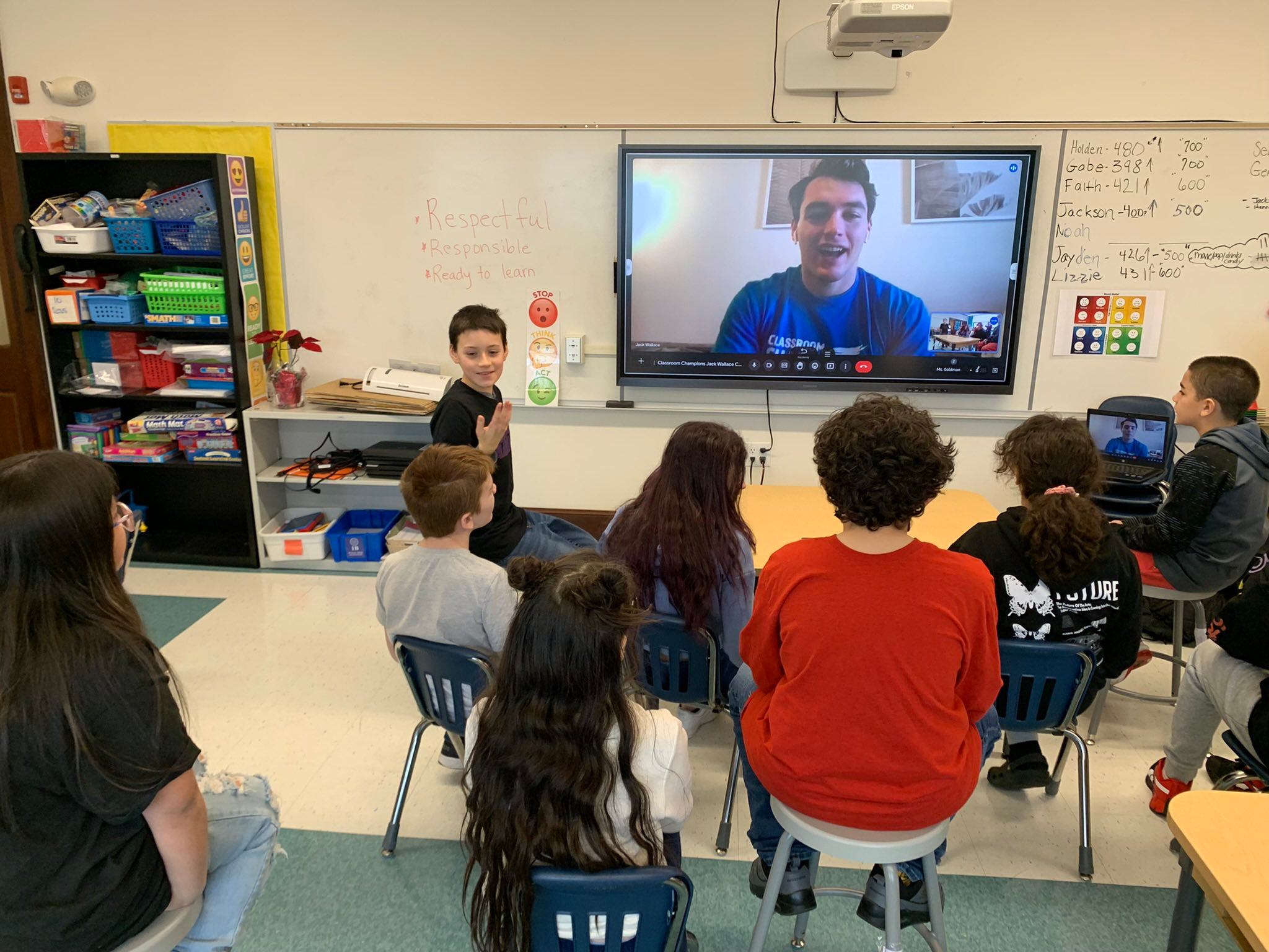 Students gather around a screen for a video call with a Classroom Champions athlete mentor.