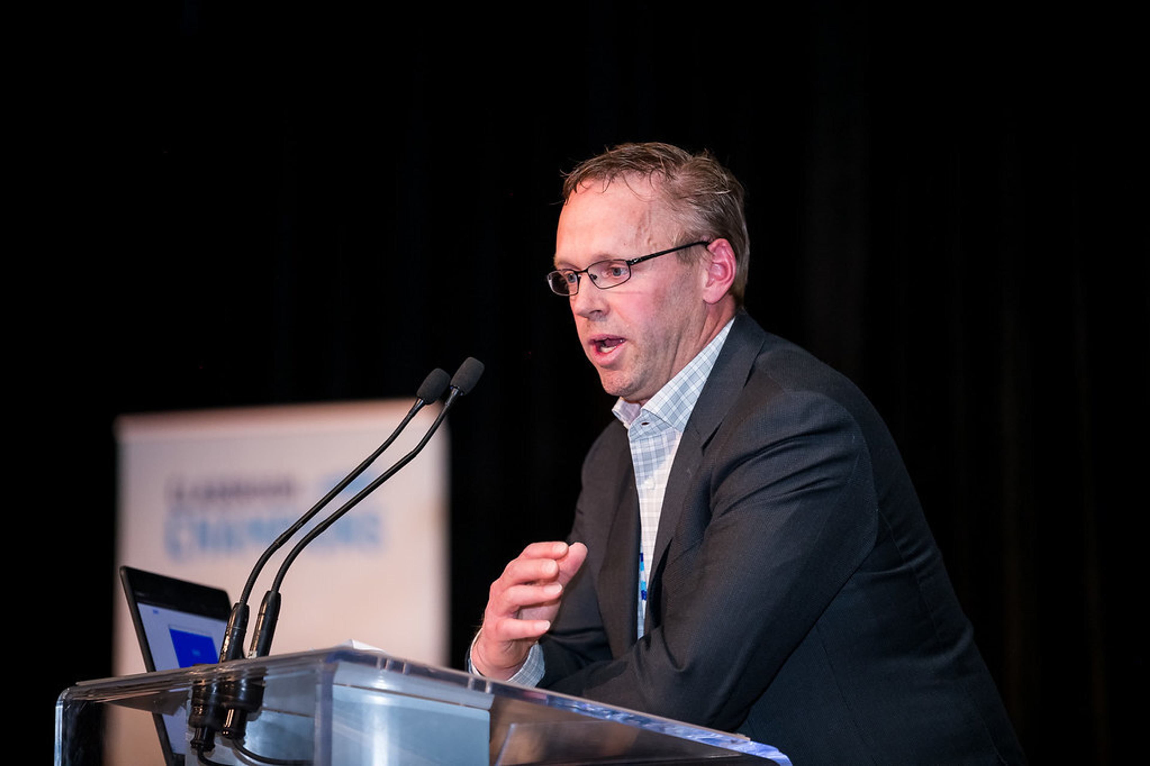 A speaker addresses the audience from a podium at a Classroom Champions event.