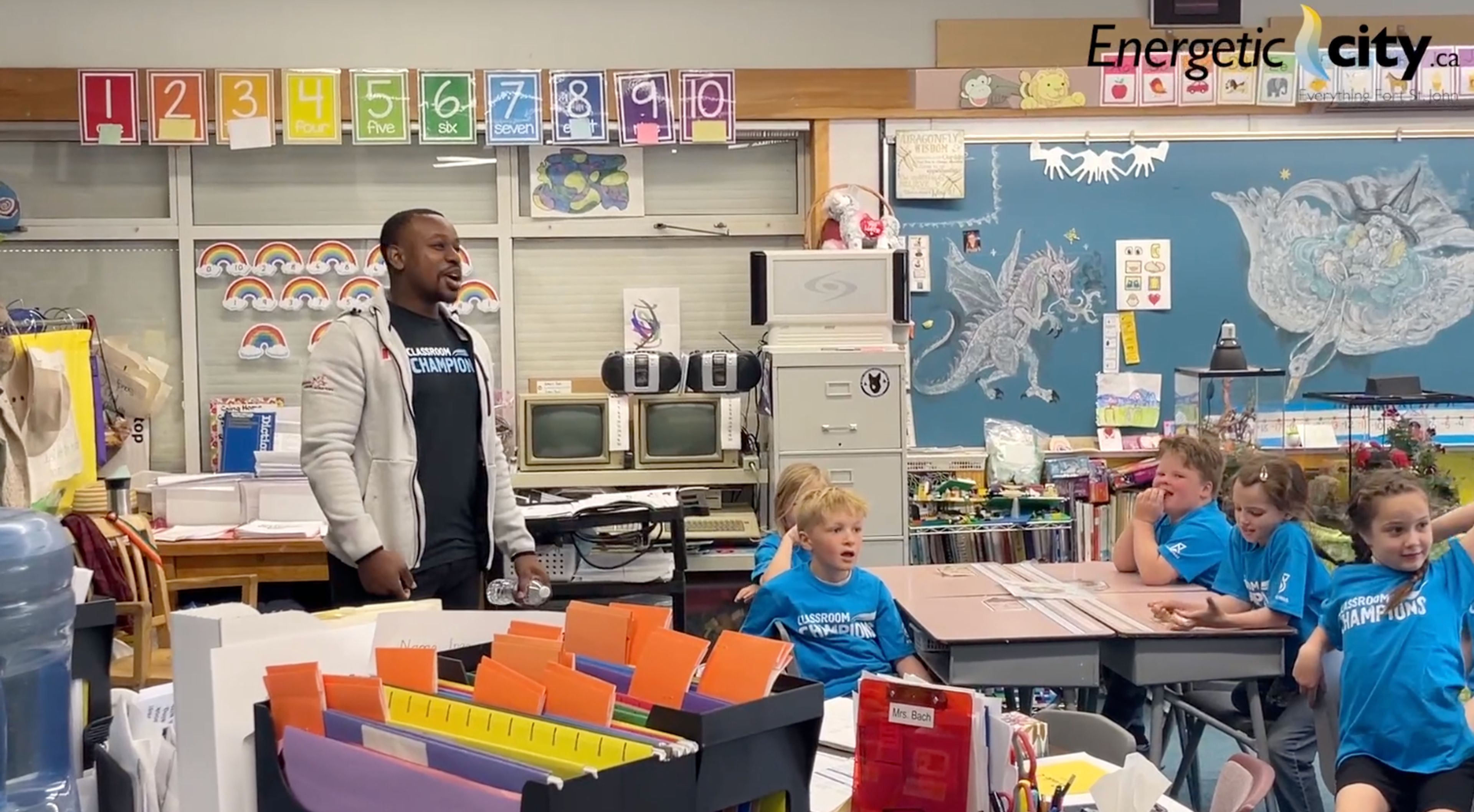 A Classroom Champions mentor speaks to students wearing Classroom Champions shirts in their classroom.