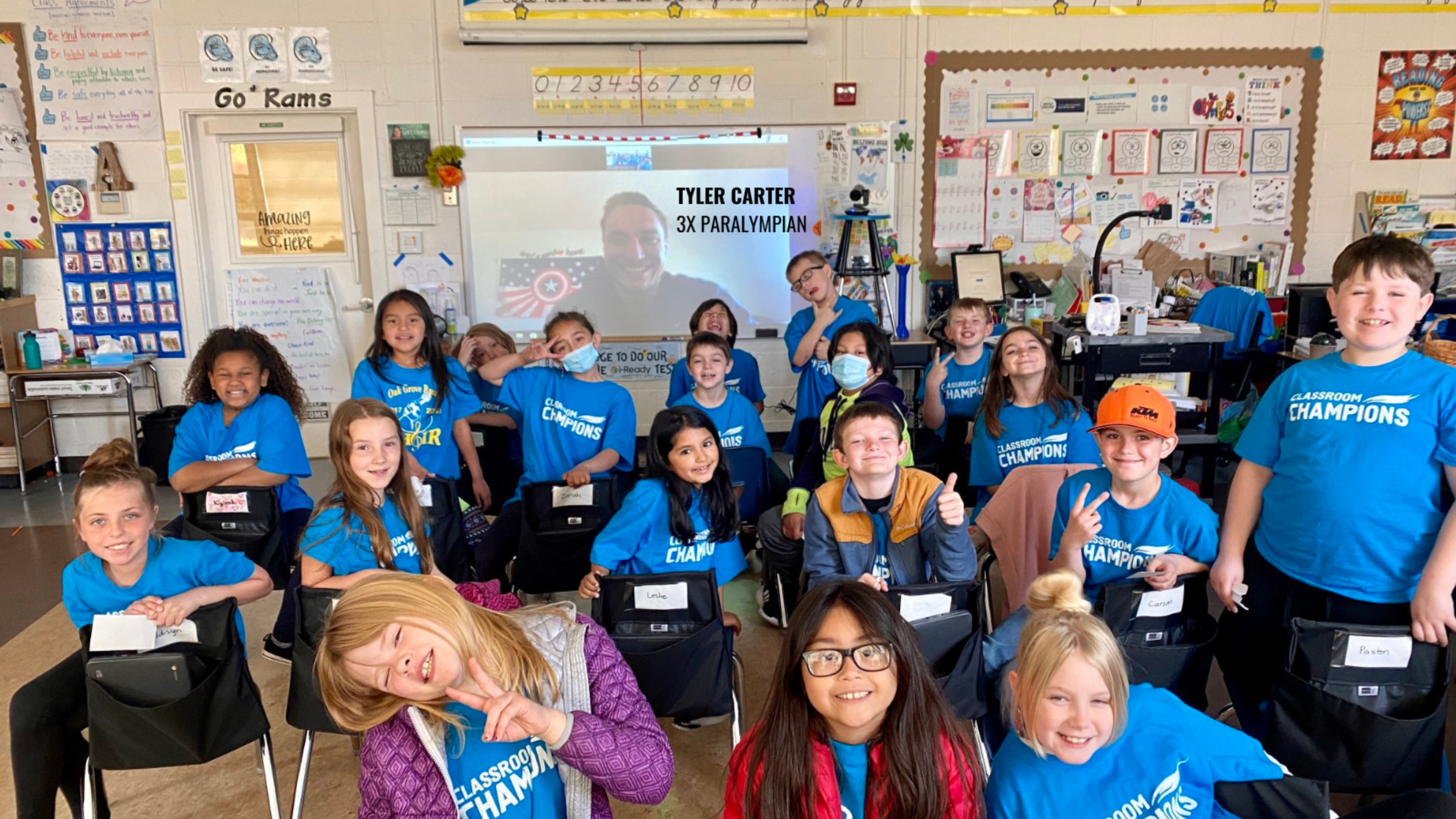 Students in Classroom Champions shirts video-chat with 3x Paralympian Tyler Carter on a classroom screen.