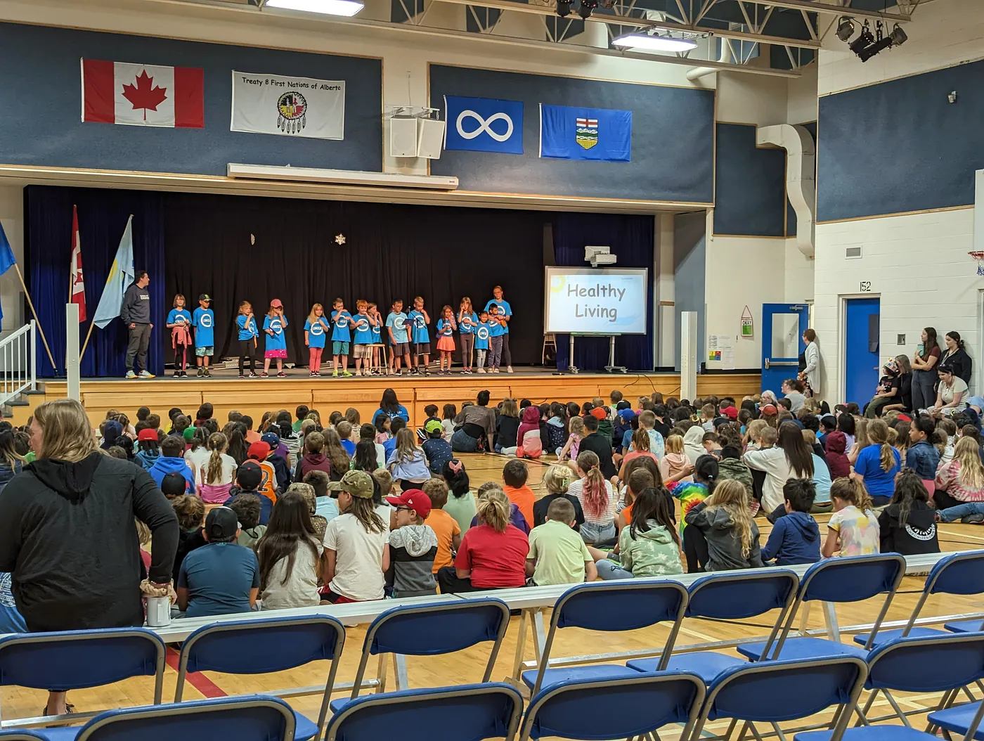 Students in matching blue shirts present on stage during a Healthy Living assembly for their school.