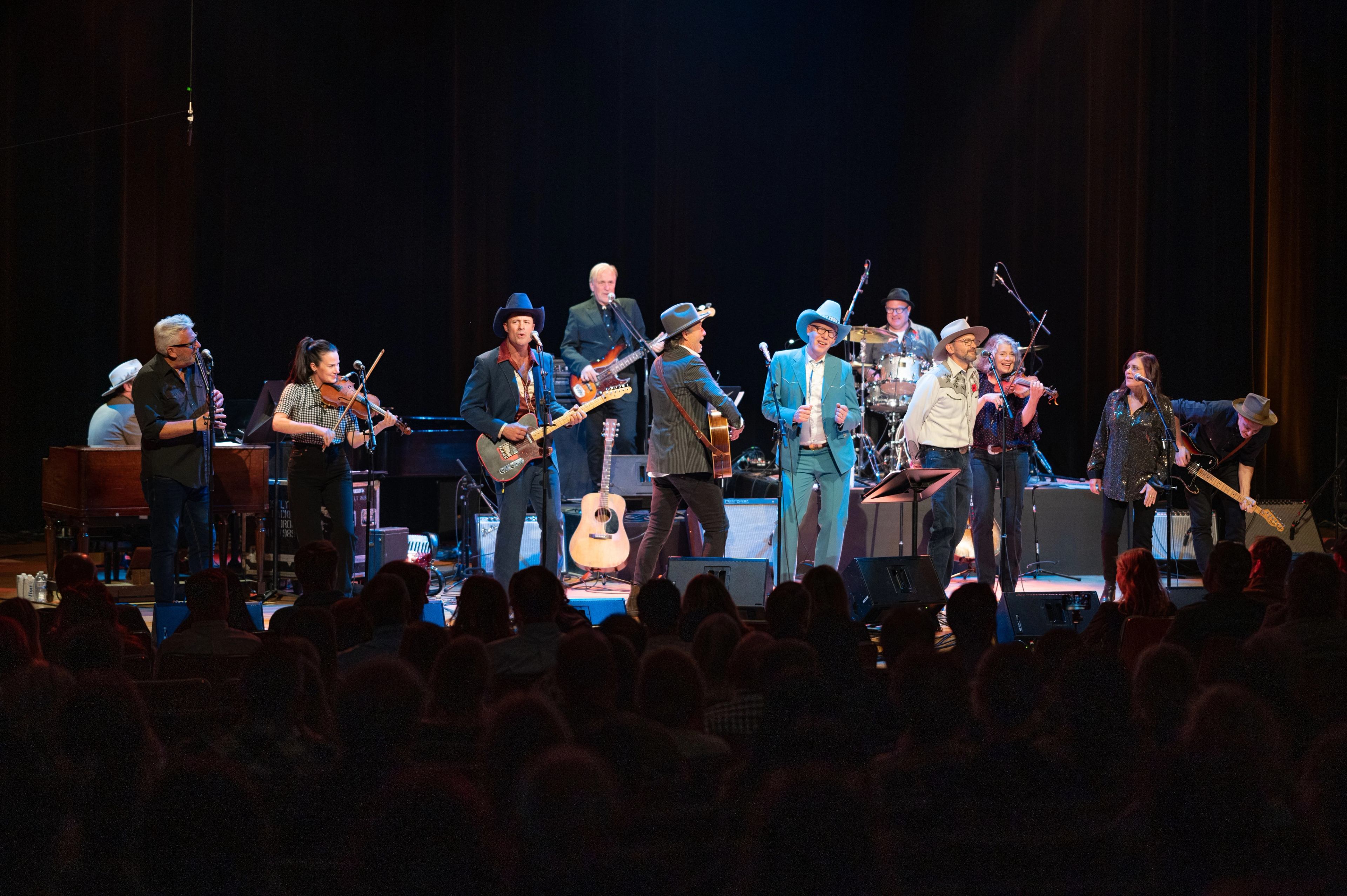 A band of musicians performs on stage together at the Concert for Classrooms benefit show.