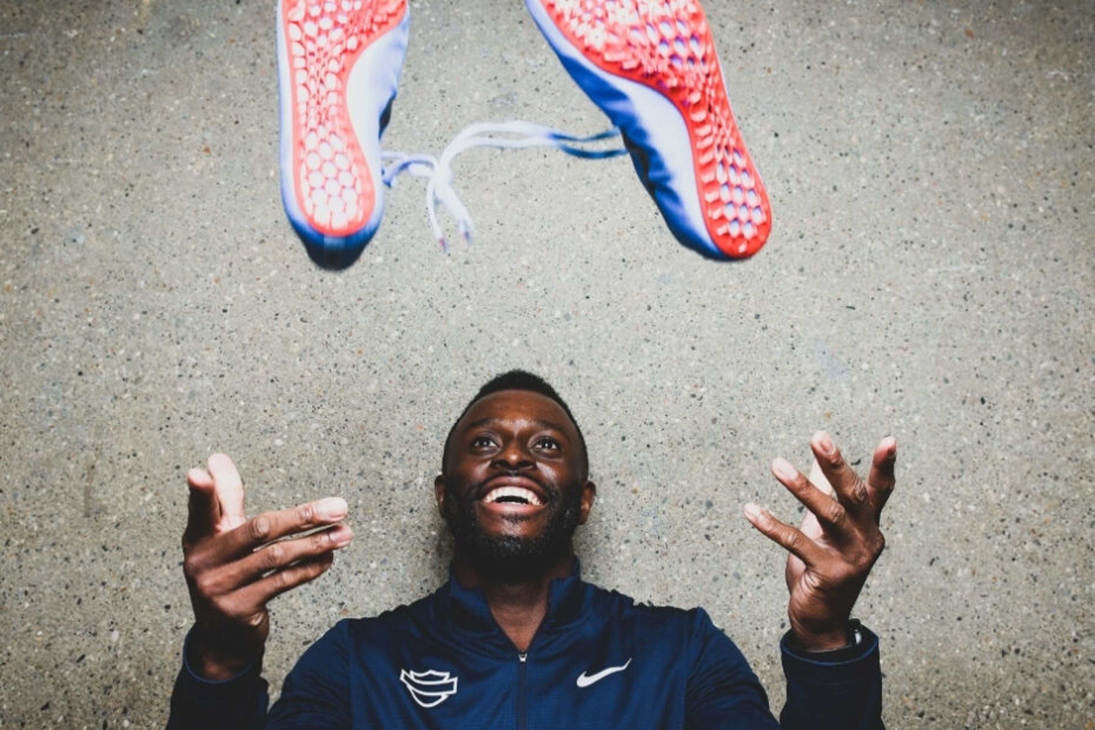 Sprinter Sam Effah smiles while tossing his running shoes into the air.