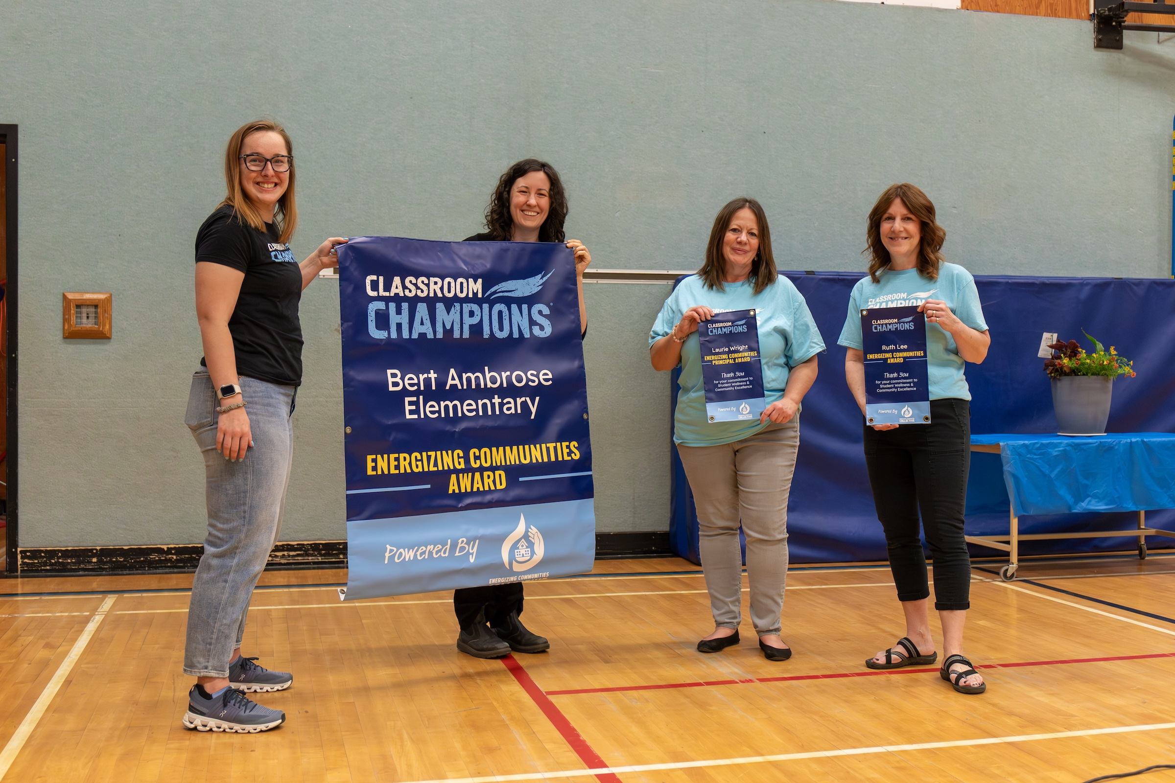 Bert Ambrose Elementary staff hold a Classroom Champions Energizing Communities Award banner and certificates.