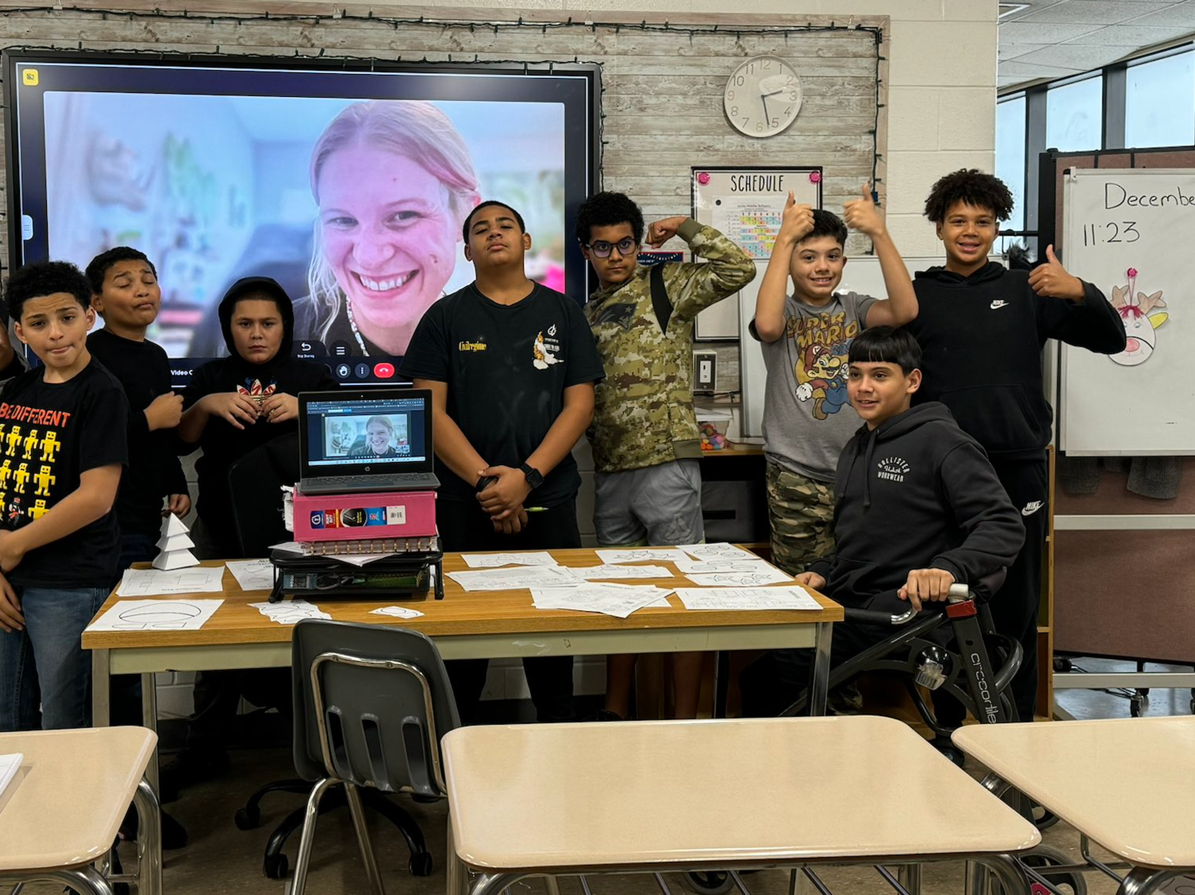 Students gather around a classroom screen for a video call with their athlete mentor.