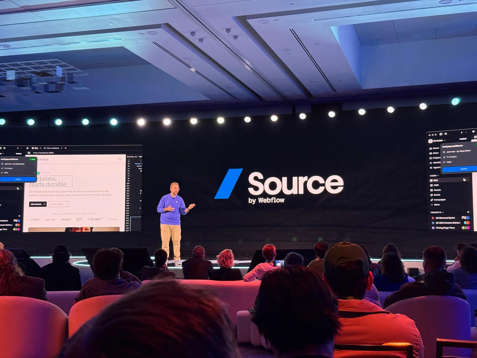 Presenter introducing Source by Webflow on stage at Webflow Conf 2026, with the Source interface displayed on large screens behind him.