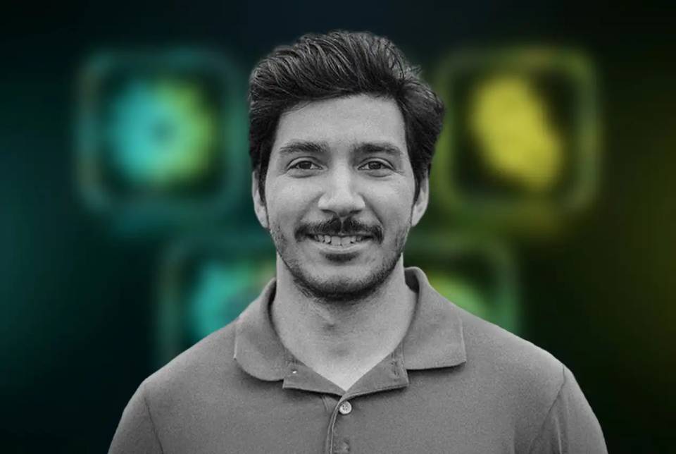 Portrait of Josiah smiling against a blurred green background.
