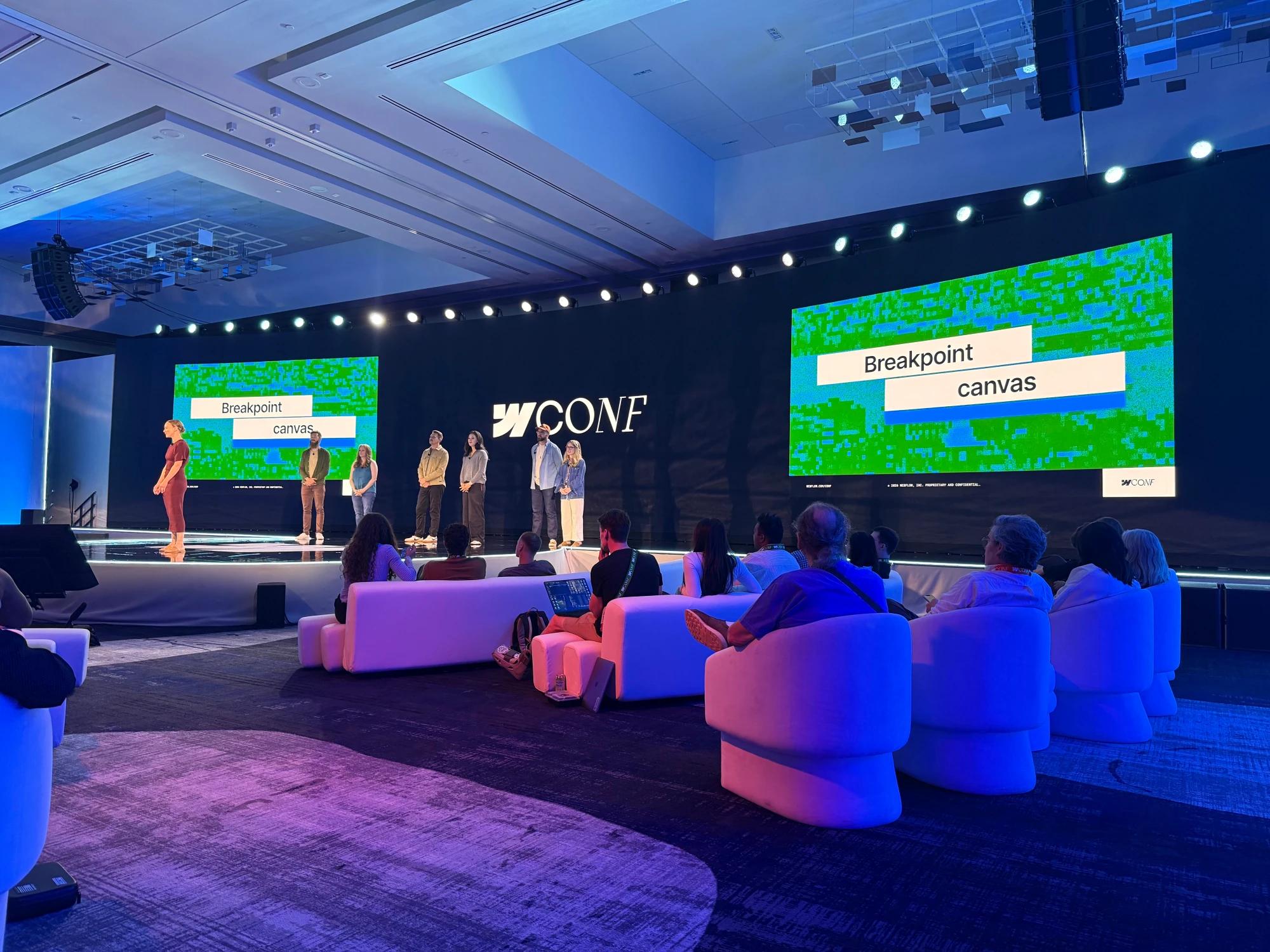Presenters on stage at Webflow Conf, with screens displaying “Breakpoint canvas” and attendees seated in the foreground.