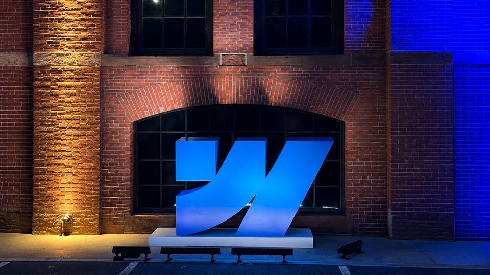 Large illuminated Webflow logo installation displayed against a brick wall at Webflow Conf 2026.