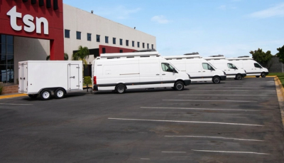 Flota de vans blancas TSN estacionadas frente a edificio corporativo