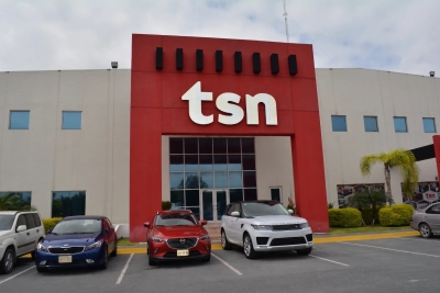 Modern TSN building with large red facade and white TSN letters, cars parked in front, showing corporate headquarters and branding