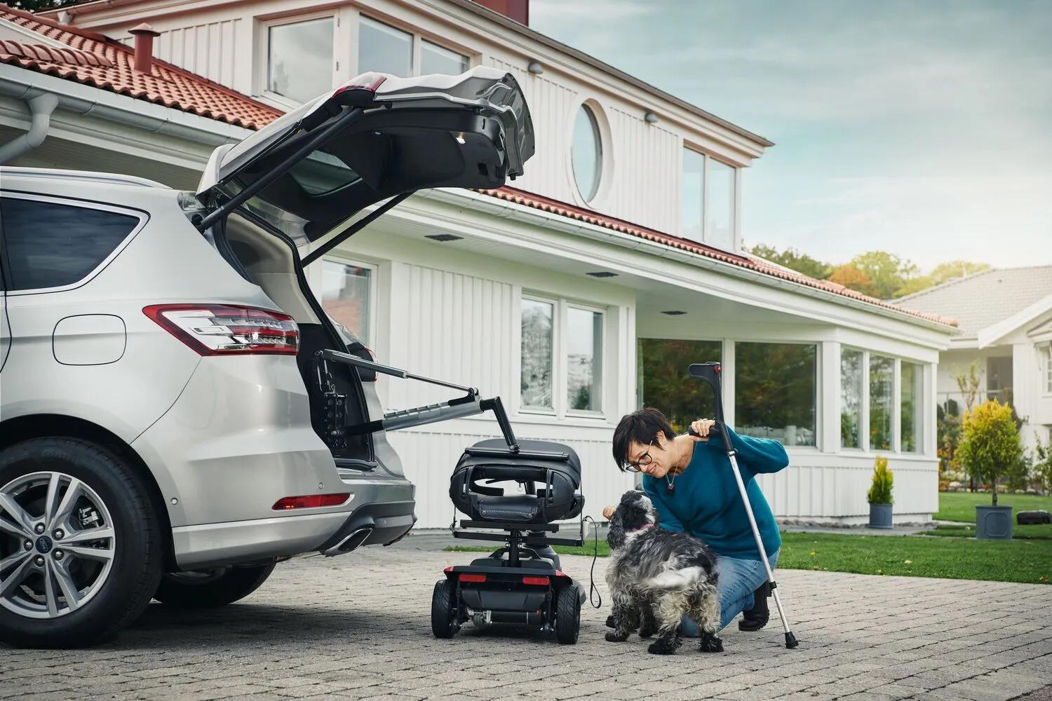 Silver SUV with Carolift wheelchair hoist lifting mobility scooter into open trunk