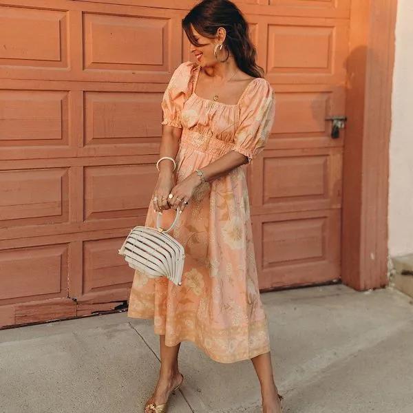 Woman wearing orange Spell dress.