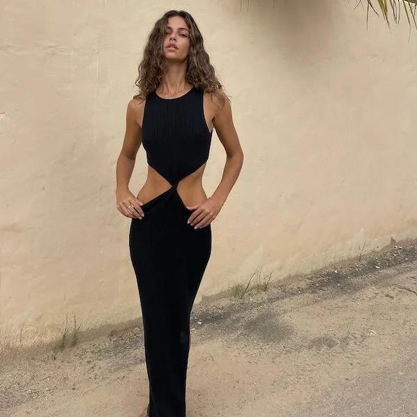 Model wearing long, black dress with cut outs on the hips from Bec & Bridge.
