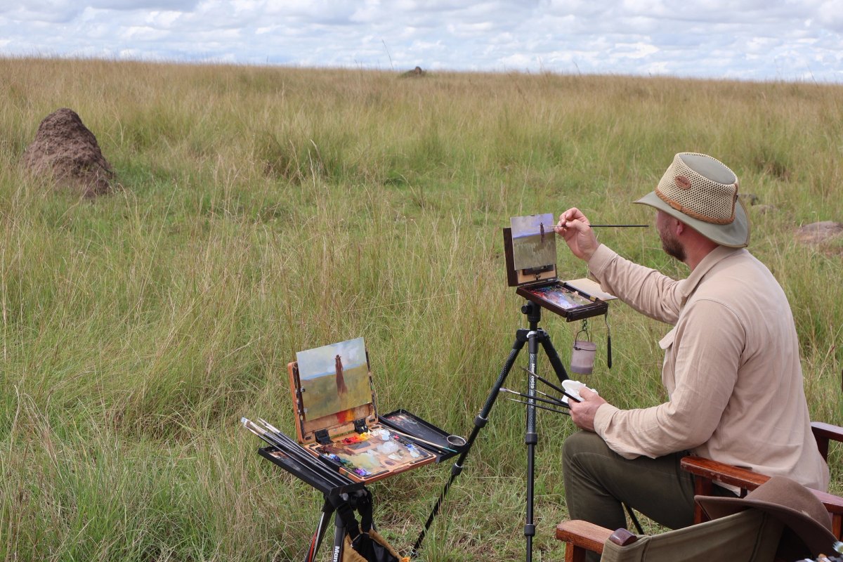 An artist painting outdoors in the African grasslands