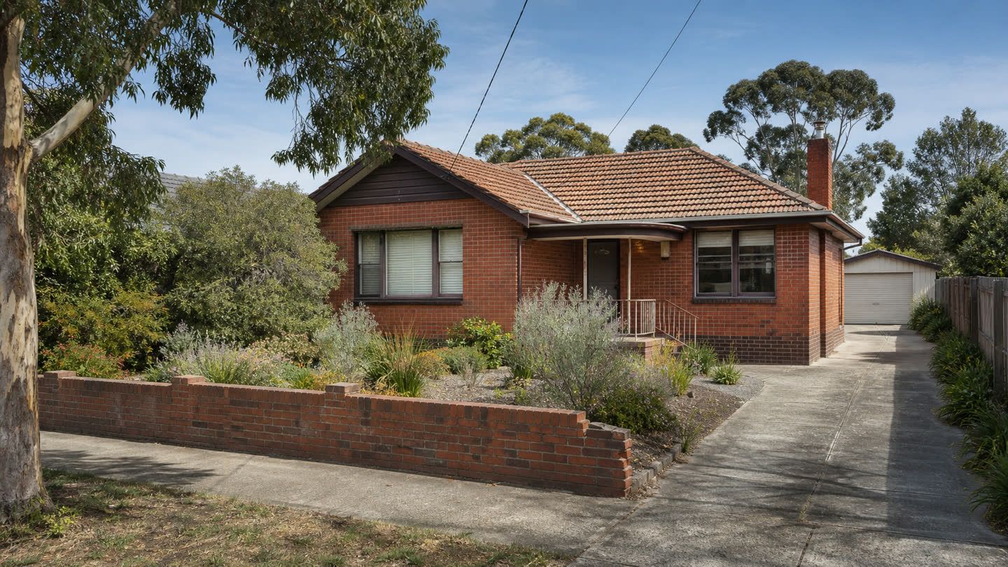 A red-brick Australian suburban home with a tiled roof and established front garden