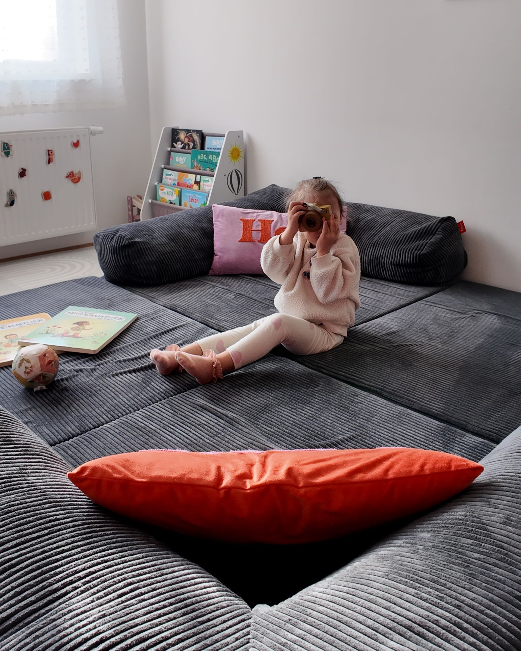Ein Foto von einem Kind mit einer Spielzeug-Kamera auf dem Funzy Family Sofa