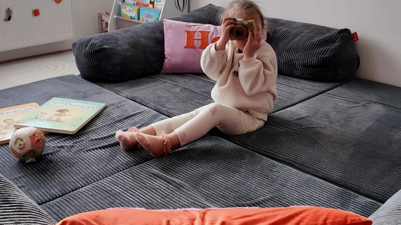 Ein Foto von einem Kind mit einer Spielzeug-Kamera auf dem Funzy Family Sofa